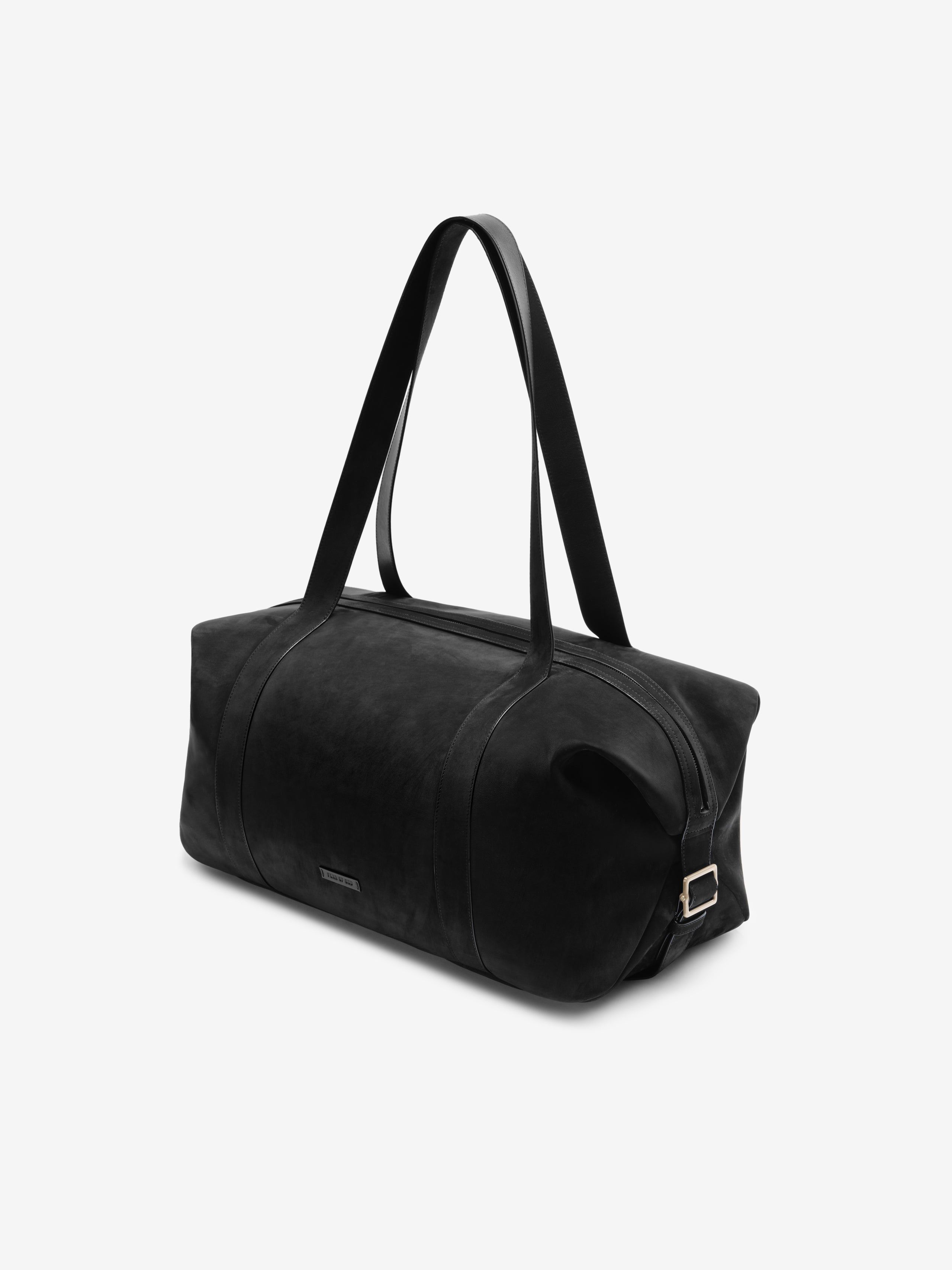 Angled view of a Large Belted Duffle in black, featuring a structured cylindrical shape, smooth leather material, and long shoulder straps for easy carrying.