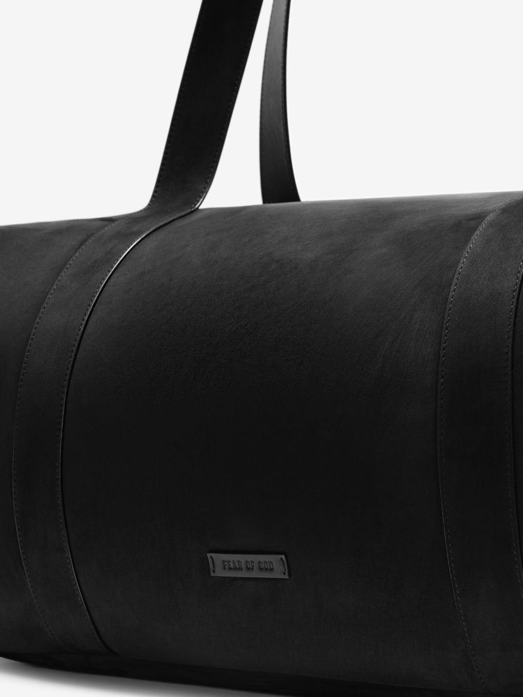 Close-up of the smooth black leather surface and strap detail on the Large Belted Duffle, featuring a subtle embossed logo for a sleek, minimalist look.