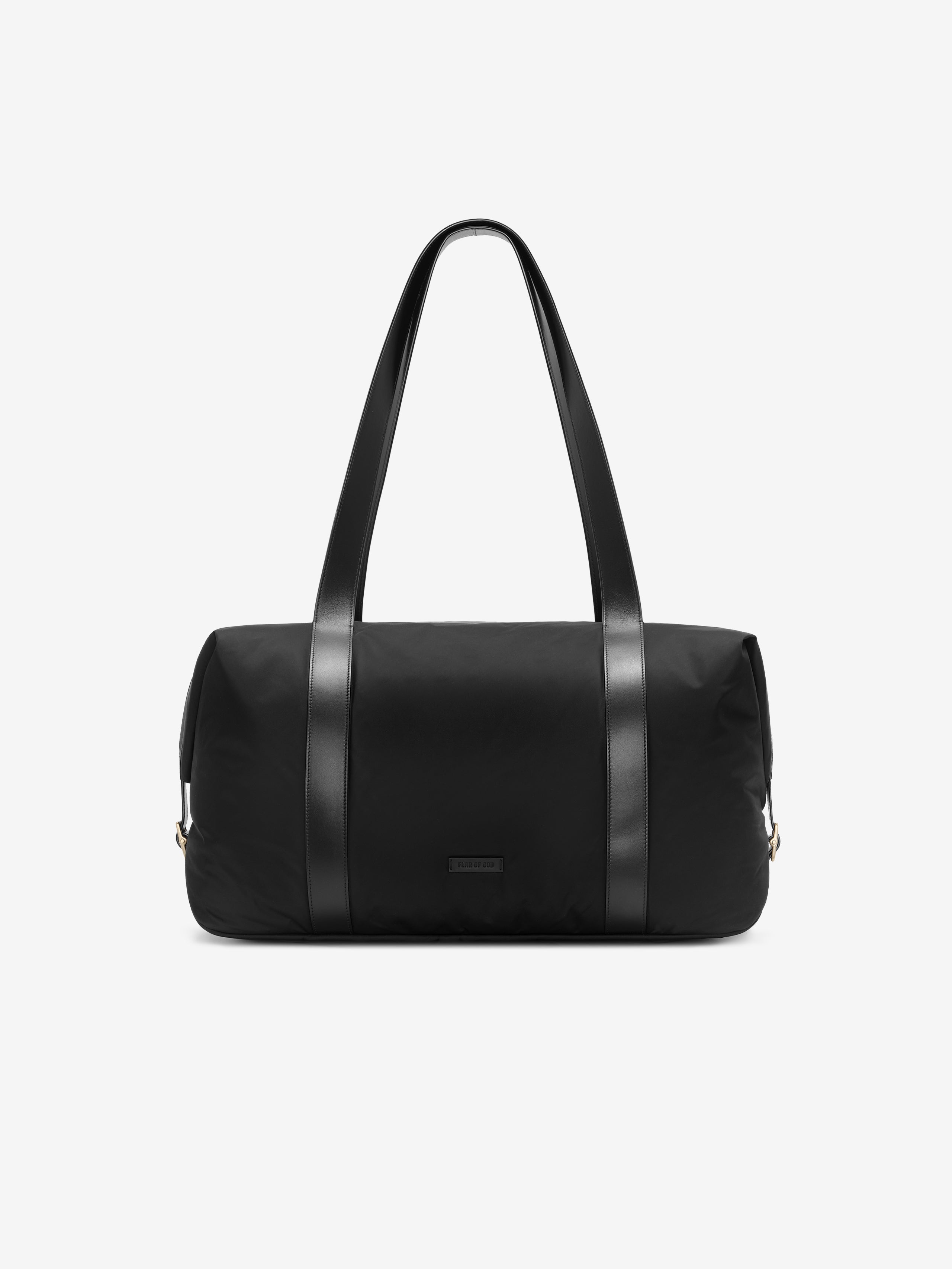 Black nylon duffle bag with long leather handles and minimalist design against a plain background
