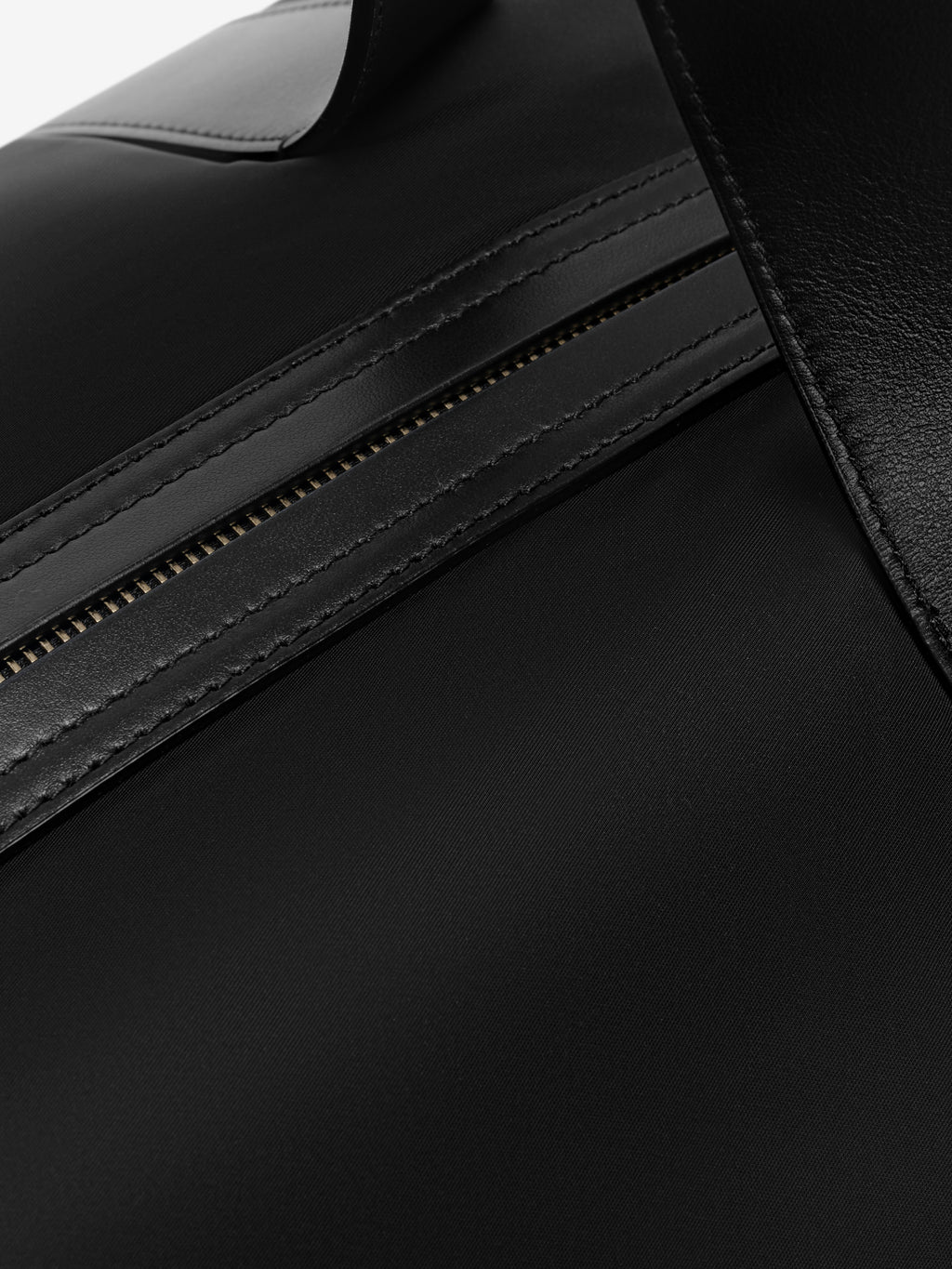 Close-up of black bag zipper with smooth leather trim and detailed stitching on durable nylon fabric surface