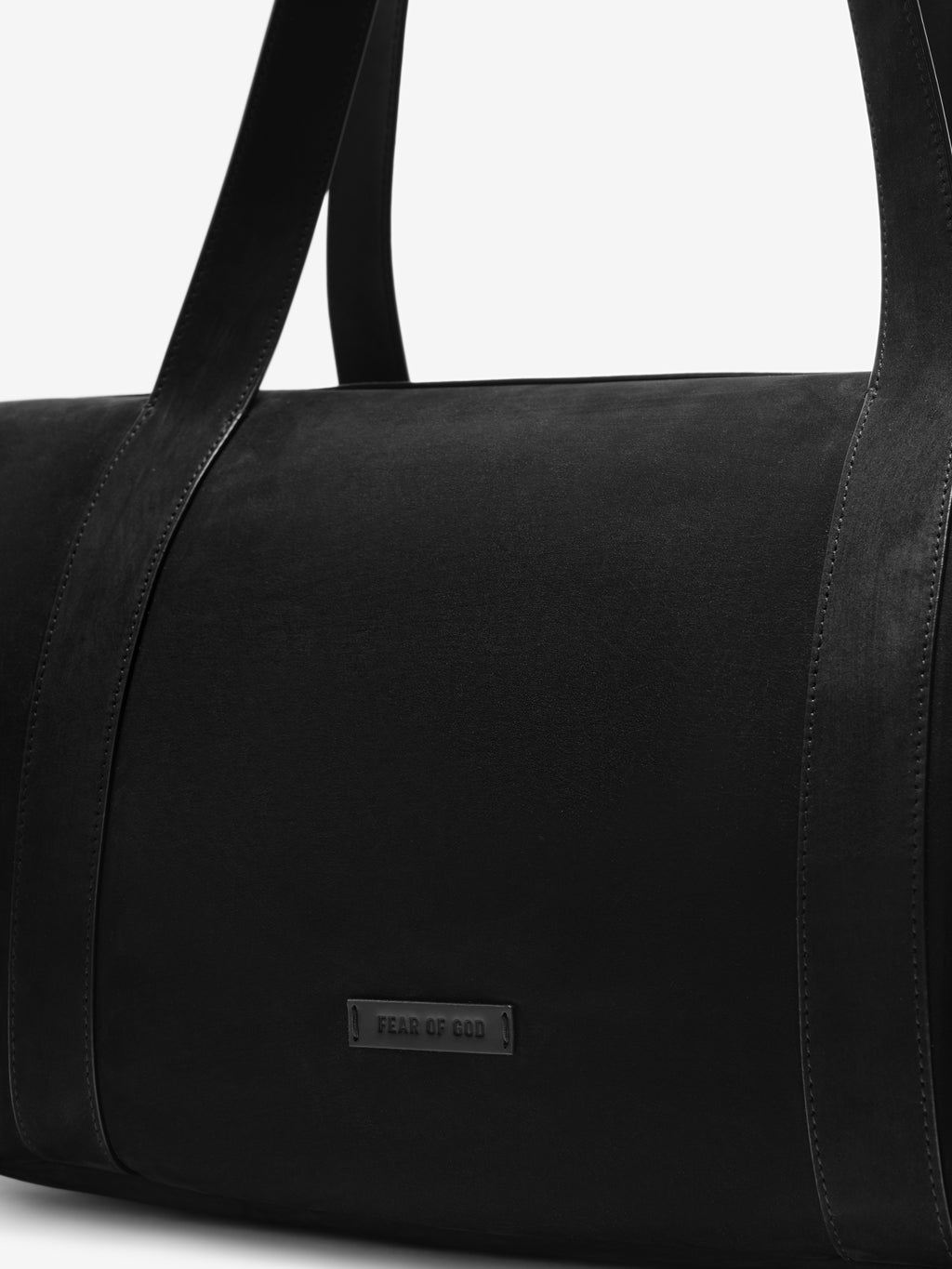Close-up of the Small Belted Duffle in black showcasing its smooth leather surface, sturdy shoulder straps, and a subtle embossed Fear of God logo plaque for a minimalist look.