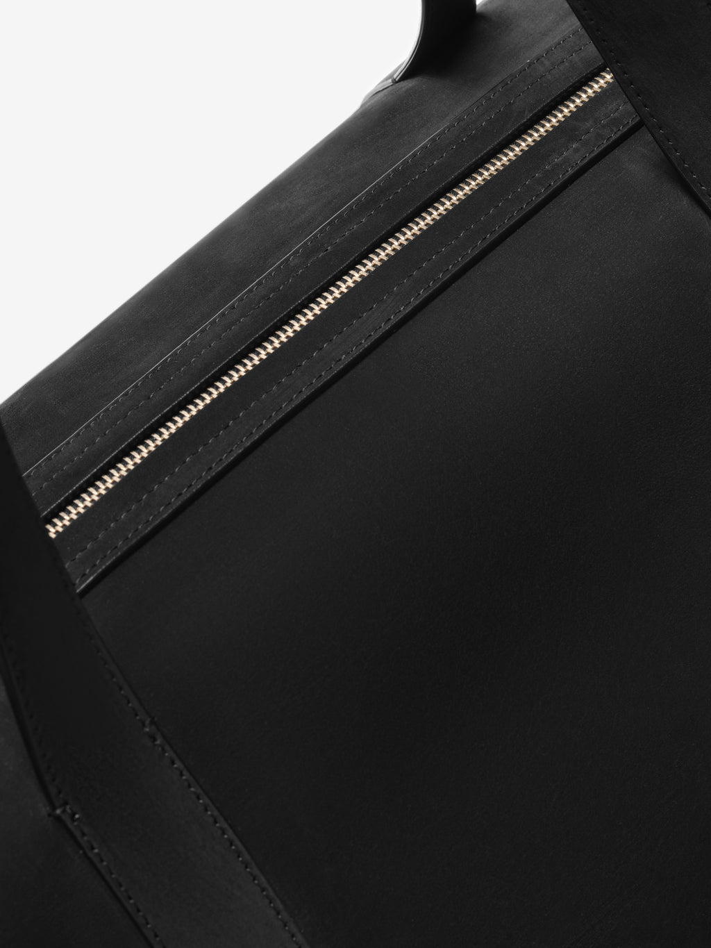 Close-up of the Small Belted Duffle in black featuring a smooth leather upper, neat tonal stitching, and a refined metal zipper with a matte finish for subtle contrast.