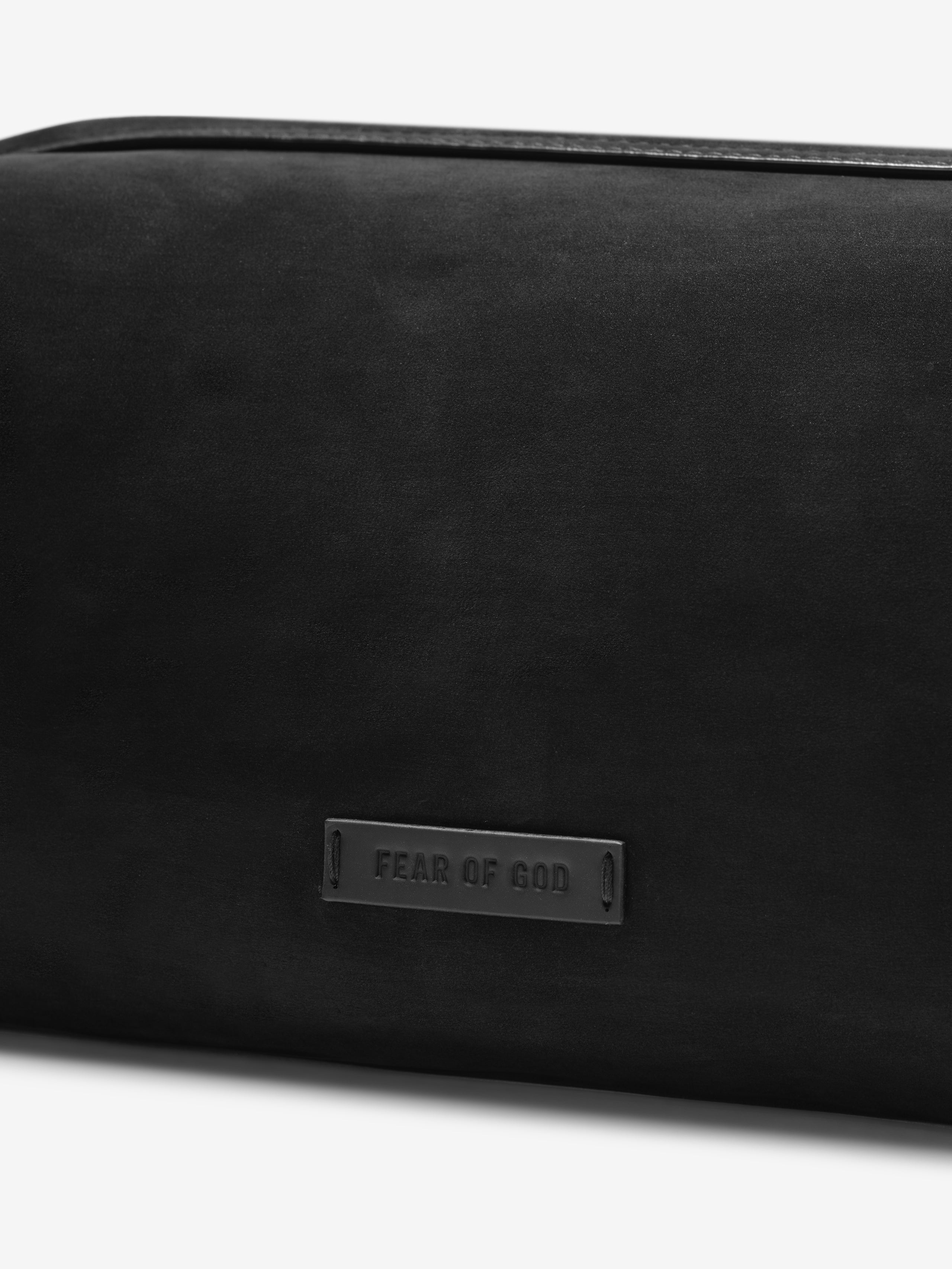 Close-up of the Nubuck Leather Belted Pouch in black showing its smooth matte finish and a subtle embossed Fear of God logo plaque on the front for a minimalist design.