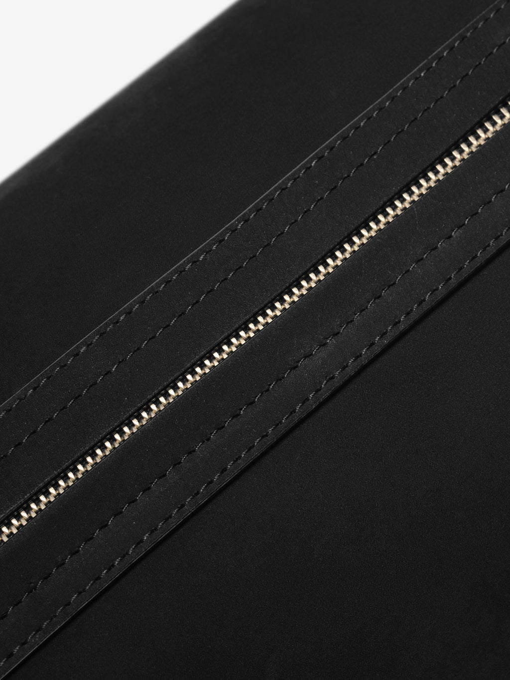 Close-up of the Nubuck Leather Belted Pouch in black, highlighting the matte textured leather and a finely stitched leather strip alongside a silver-tone zipper for a sleek, minimalist look.