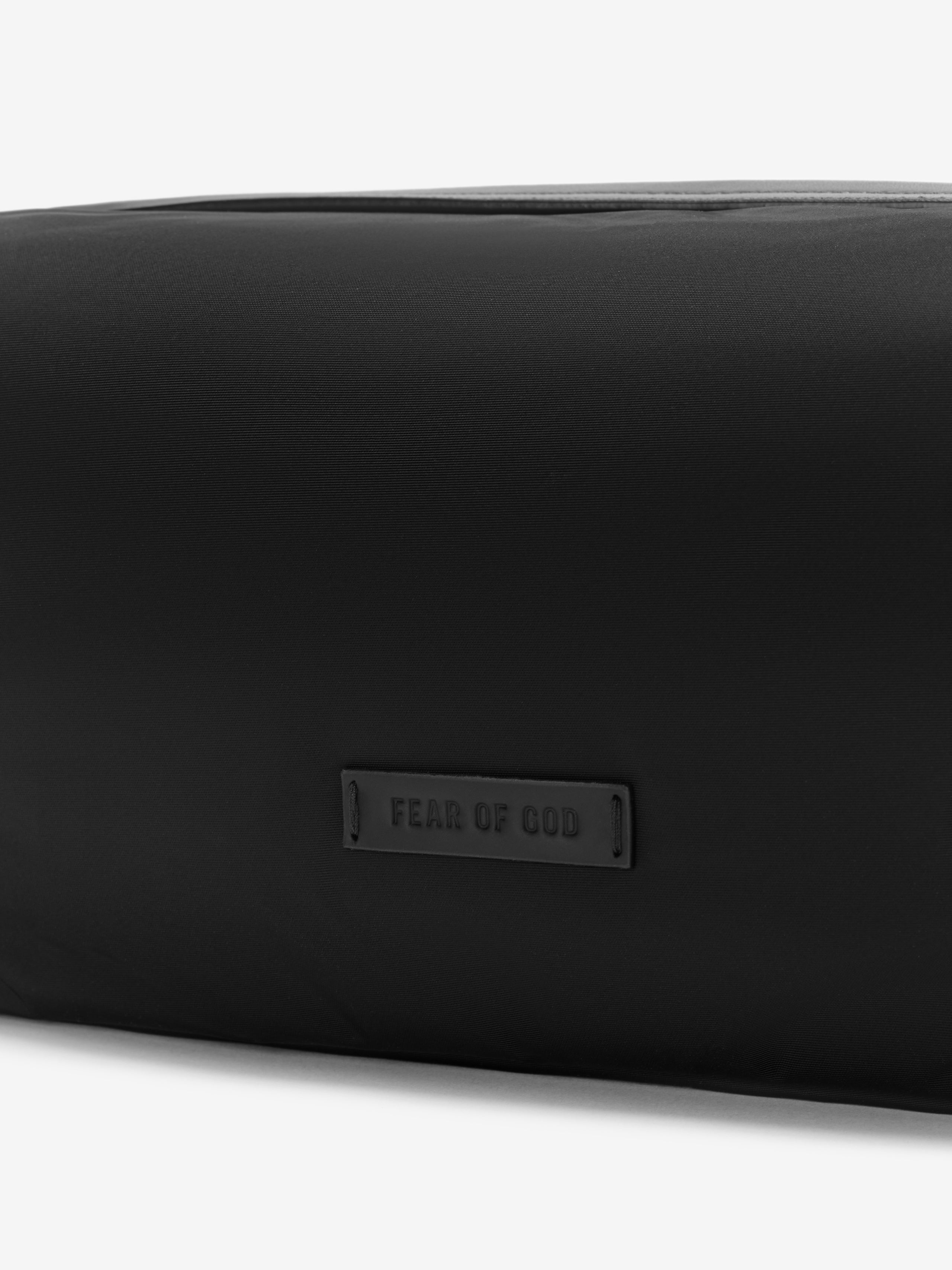 Black minimalist pouch with subtle embossed logo patch on smooth nylon fabric surface
