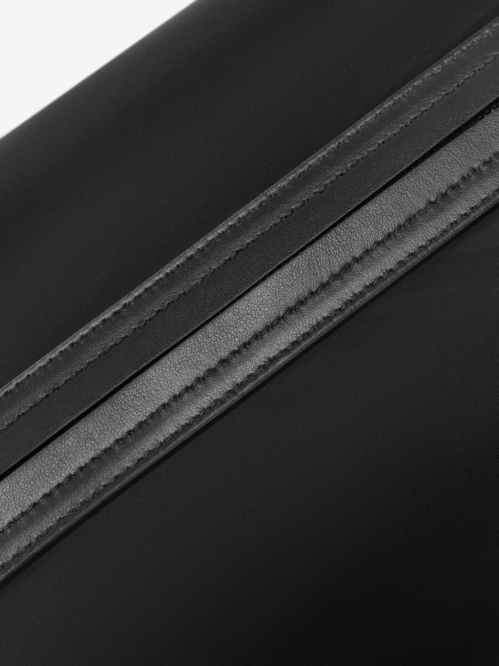 Close-up of a smooth black leather strap with detailed stitching on matte black fabric background