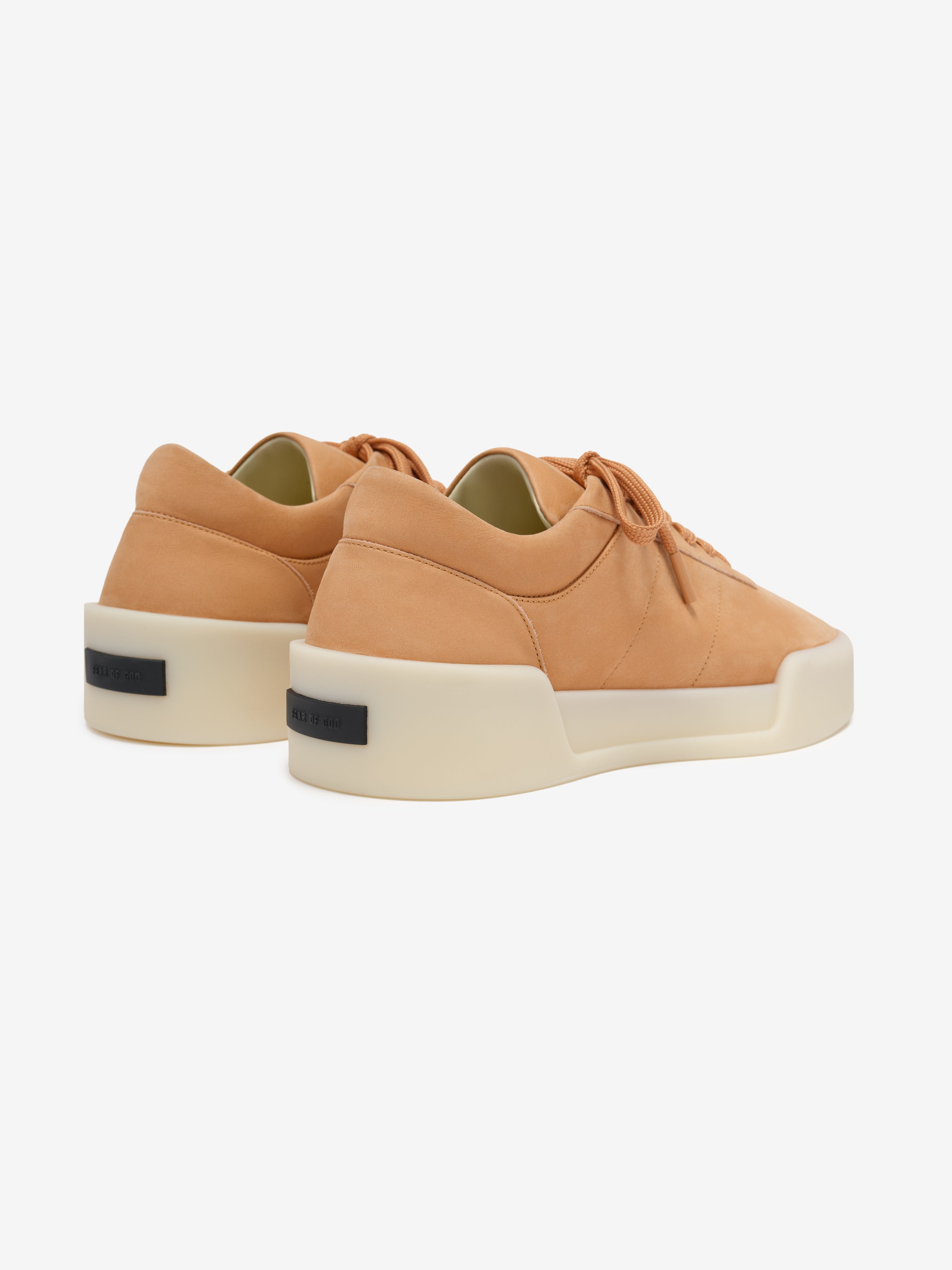 pair of tan Italian suede low-top sneakers with thick cream rubber soles viewed from rear angle