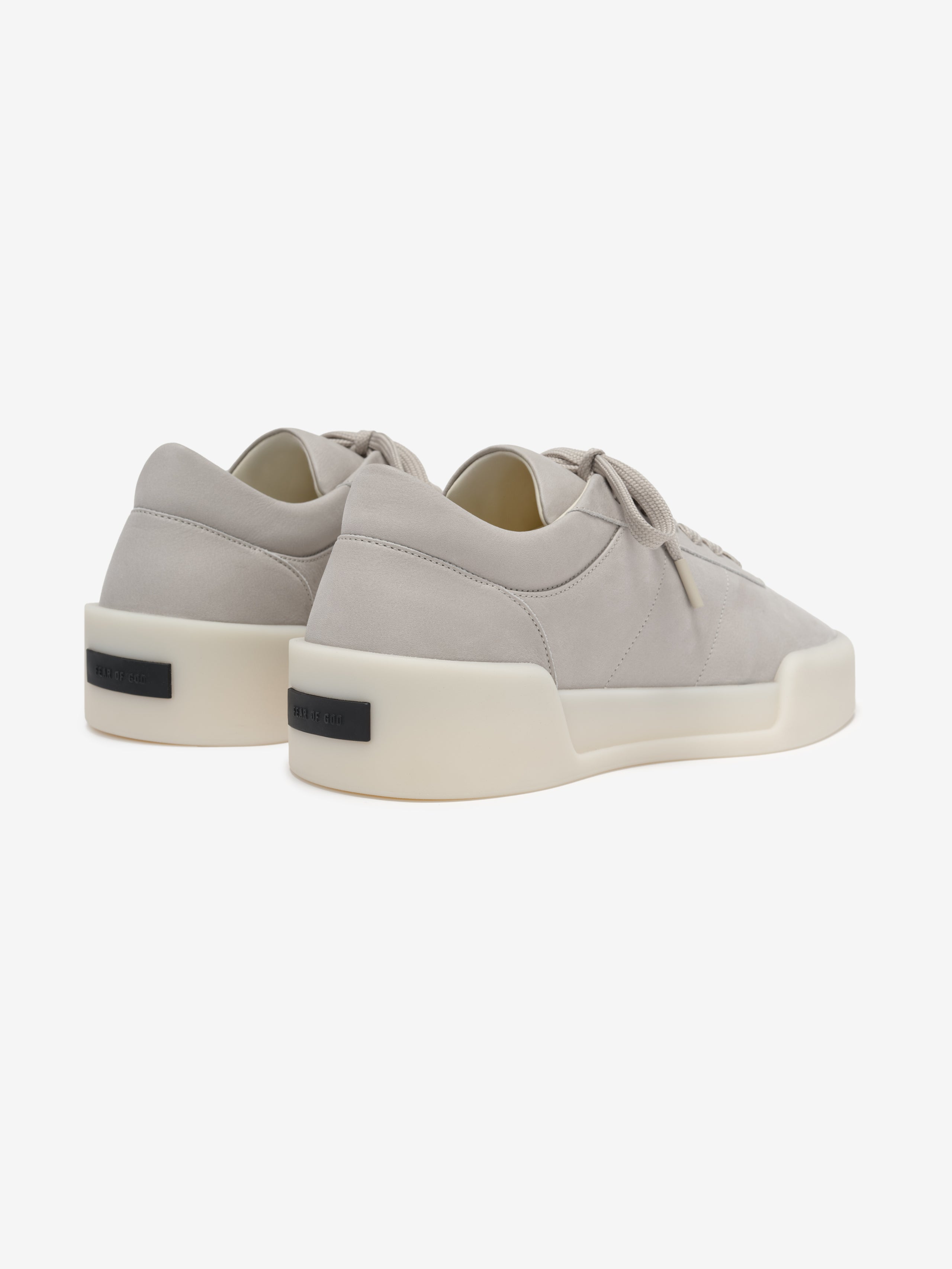 pair of beige Italian suede low-top sneakers with thick off-white rubber soles and tonal laces viewed from back angle