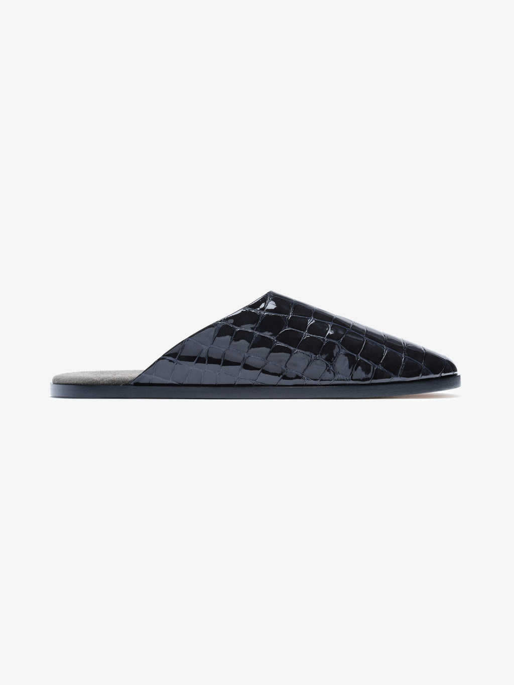 Side view of a black patent leather mule with glossy crocodile-embossed upper and flat sole on white background