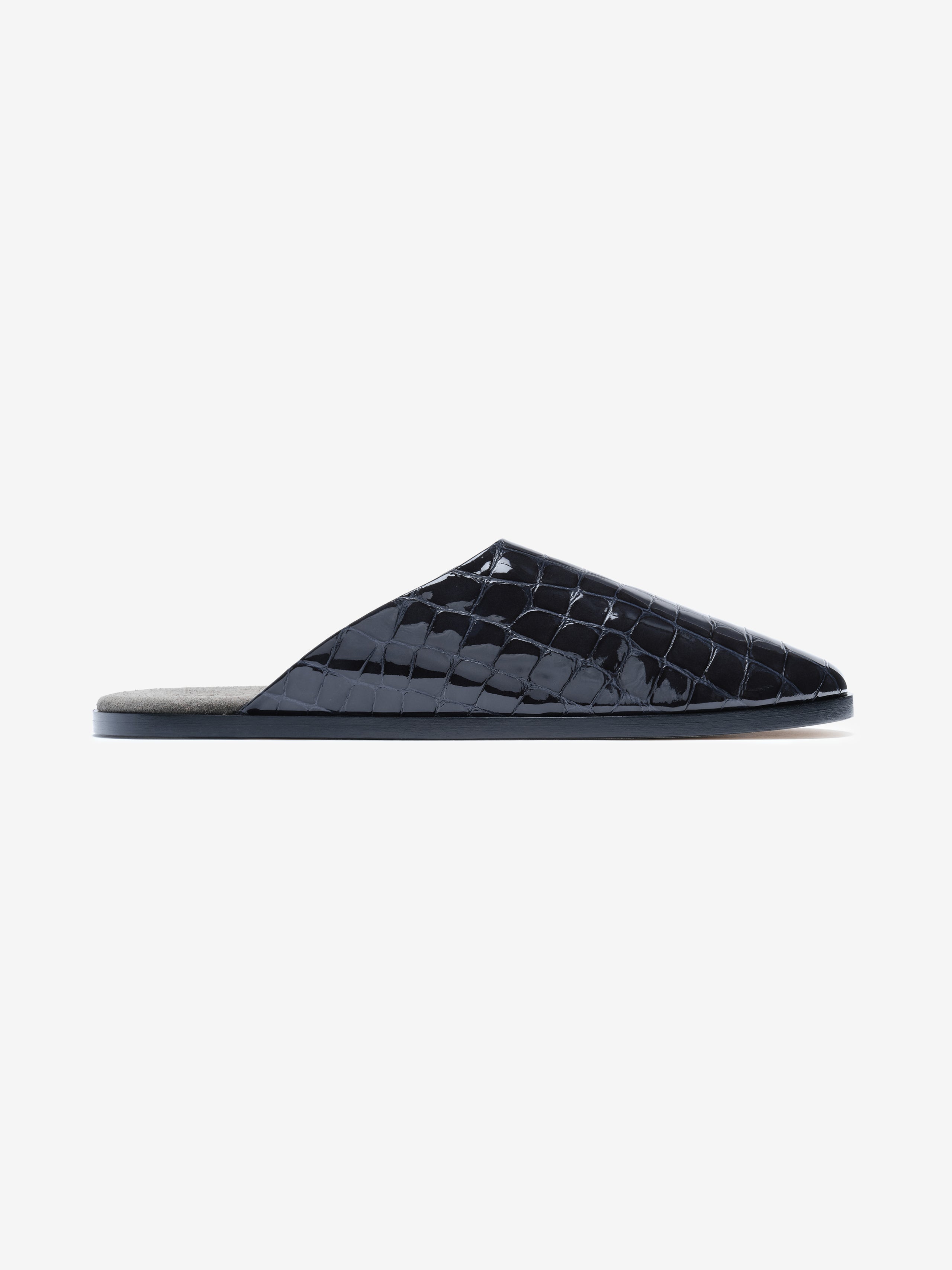 Side view of a black patent leather mule with glossy crocodile-embossed upper and flat sole on white background