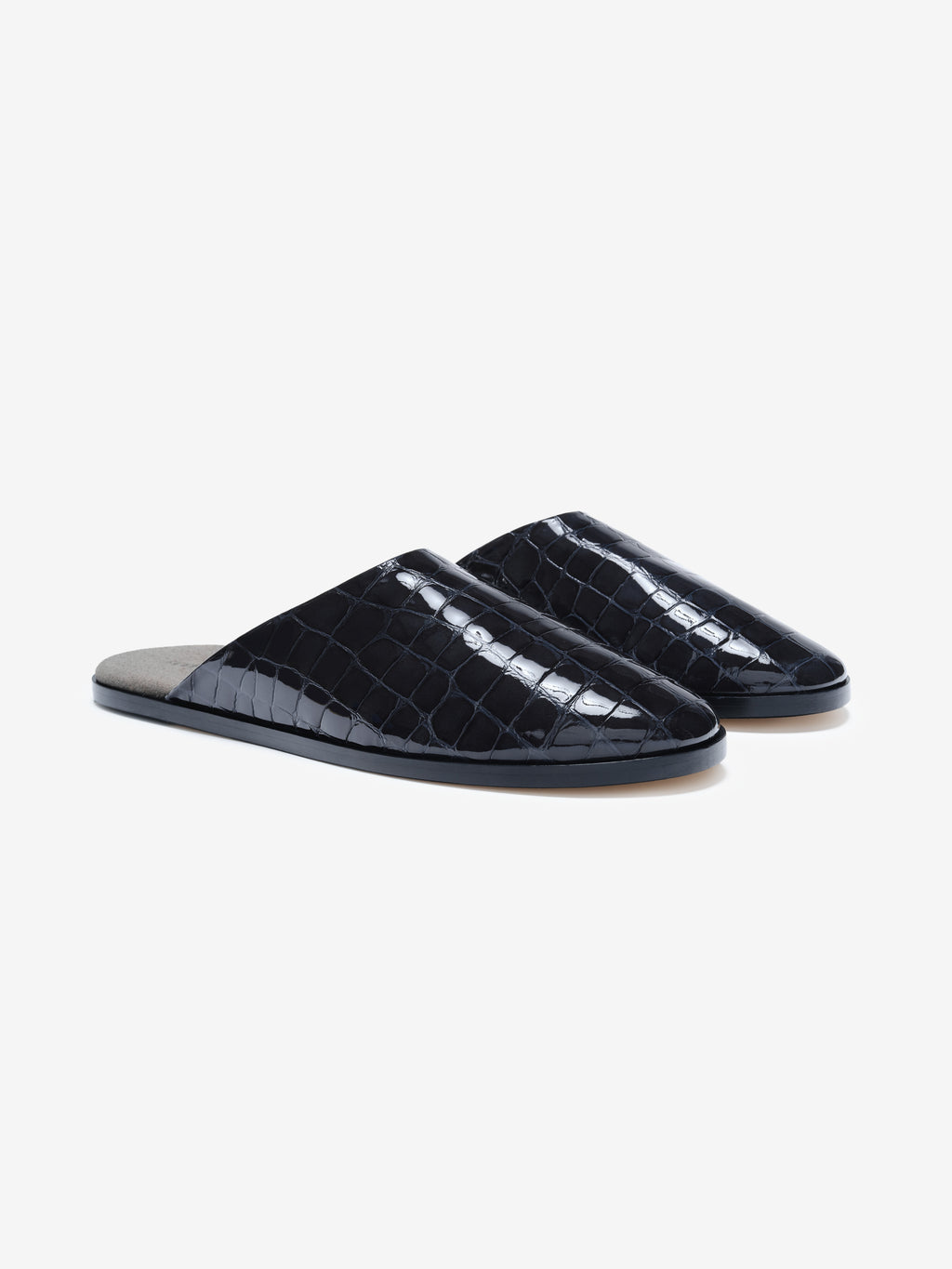 Pair of glossy black slip-on shoes with crocodile texture and flat sole on light gray background