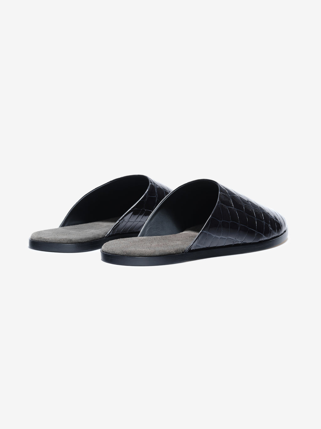 Pair of black slip-on slippers with crocodile-embossed glossy upper and soft gray insoles on a white background