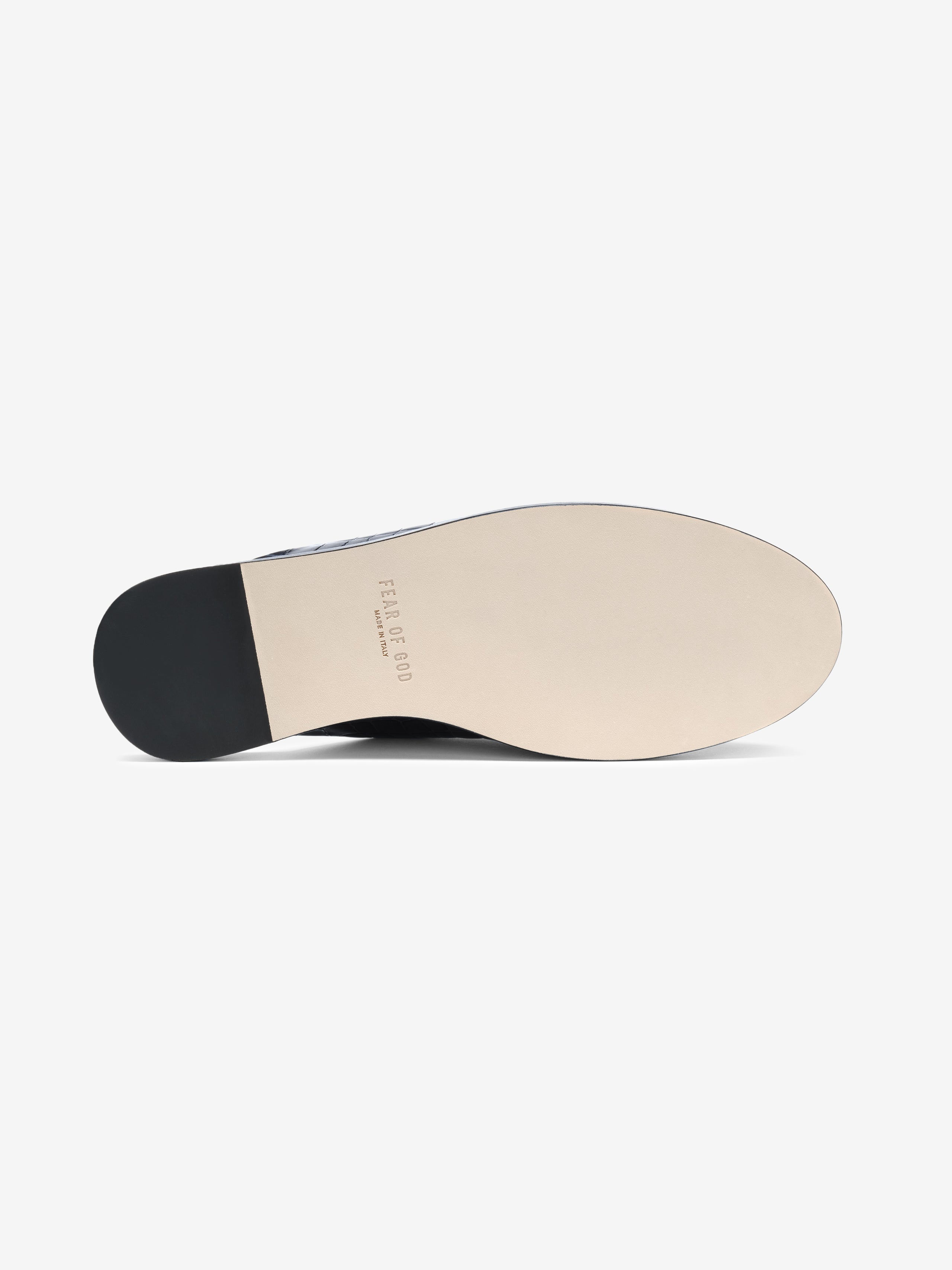 Underside view of a smooth beige shoe sole with black heel and faint embossed branding text on a white background