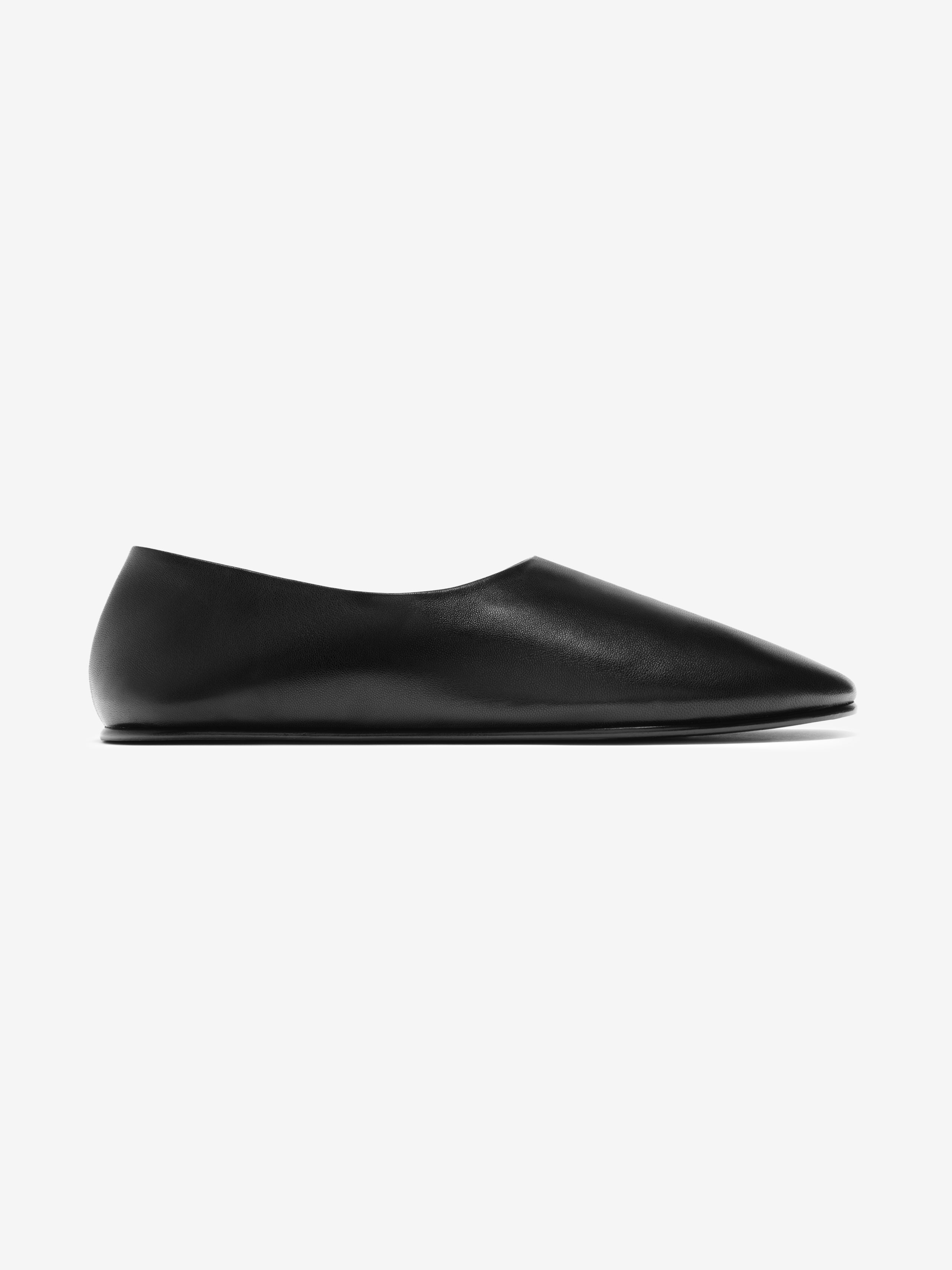 Side view of a sleek black leather pointed-toe flat shoe with a smooth matte finish on light background