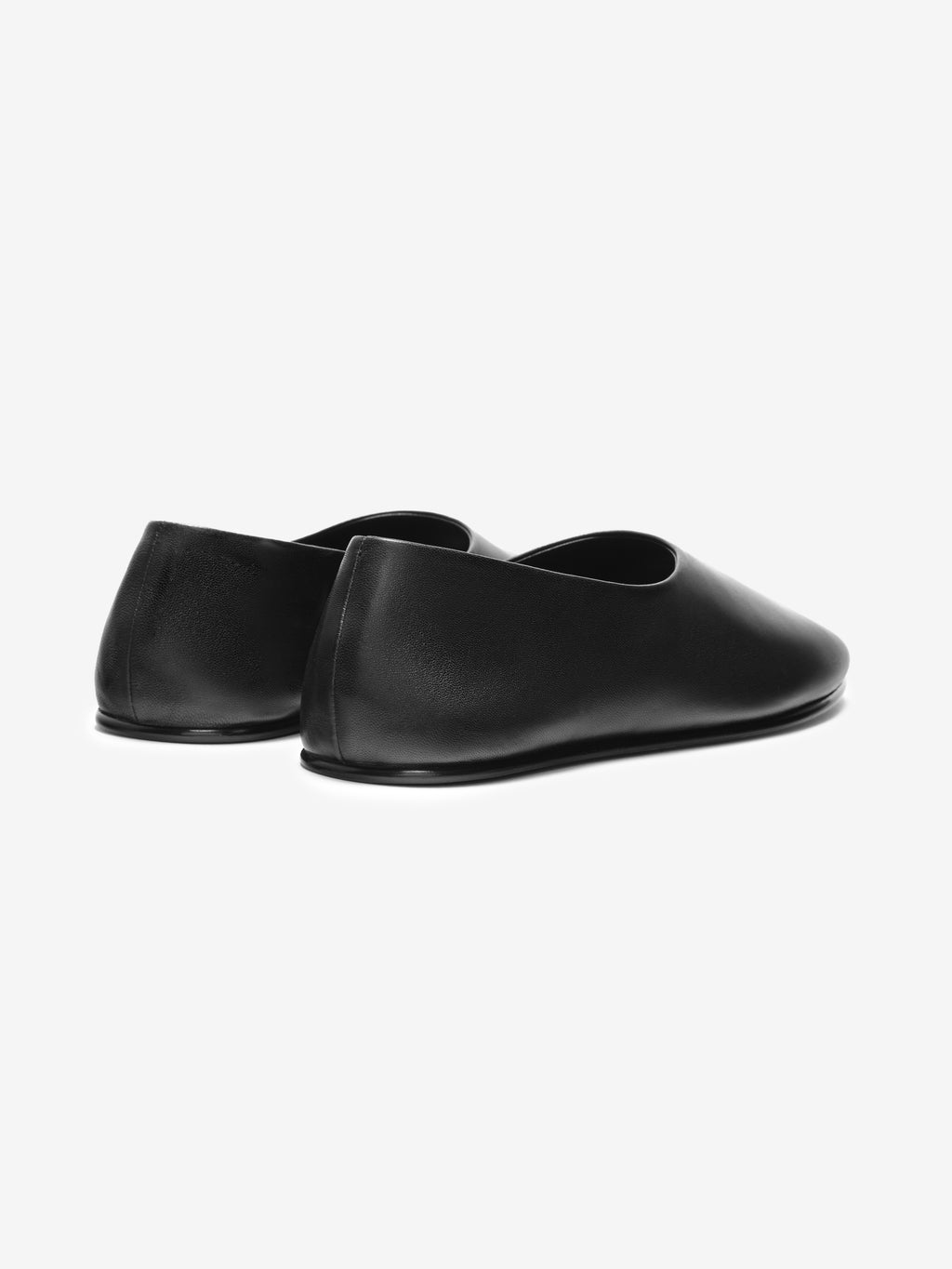 Pair of smooth black leather slip-on shoes with rounded toe and low profile sole on white background