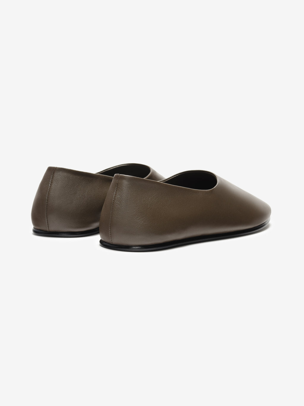 Pair of minimalist matte brown leather slip-on flats with rounded toes and low black soles on white background