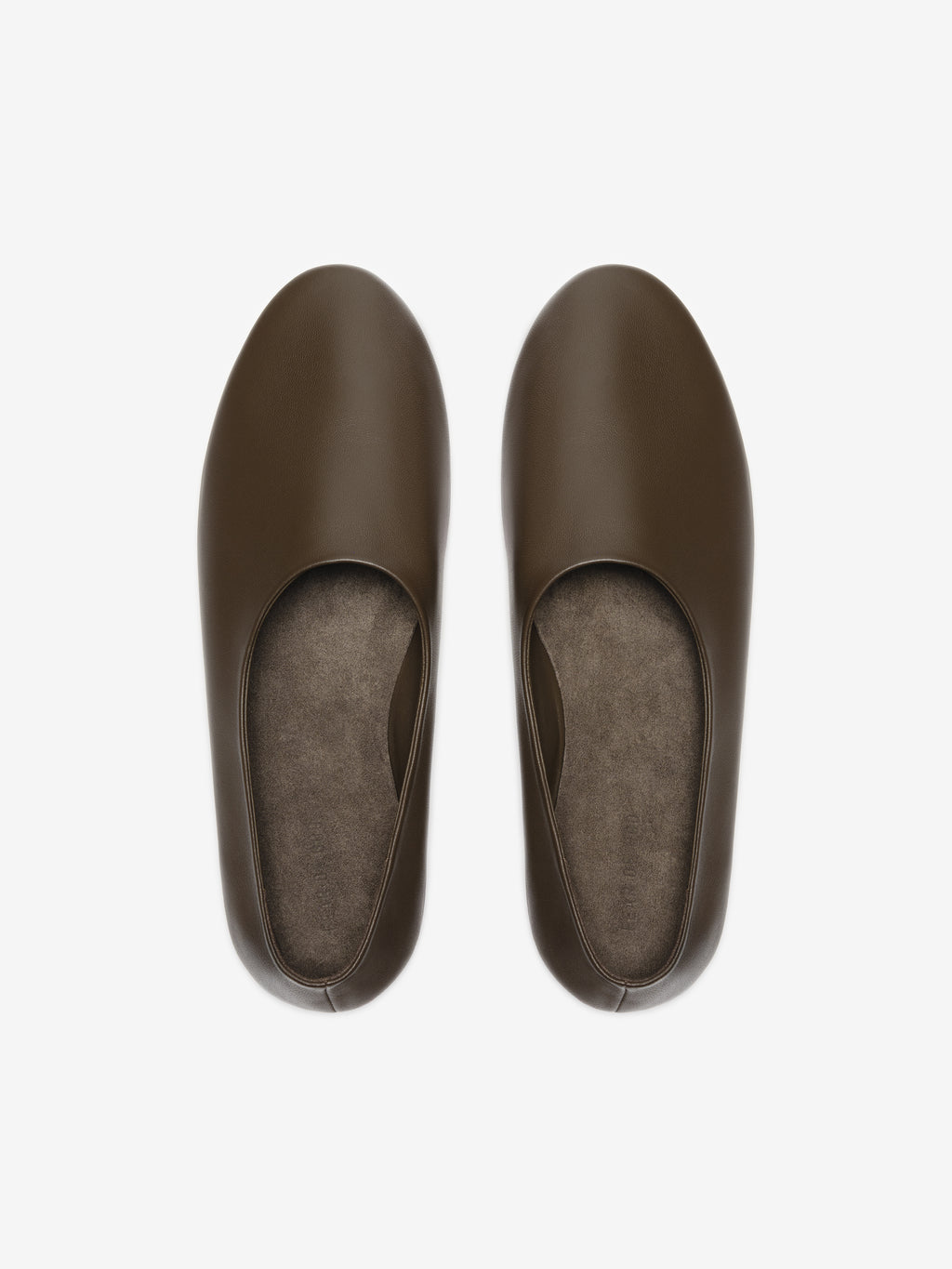 Overhead view of smooth dark brown leather slip-on flats with rounded toes and soft insoles on light background