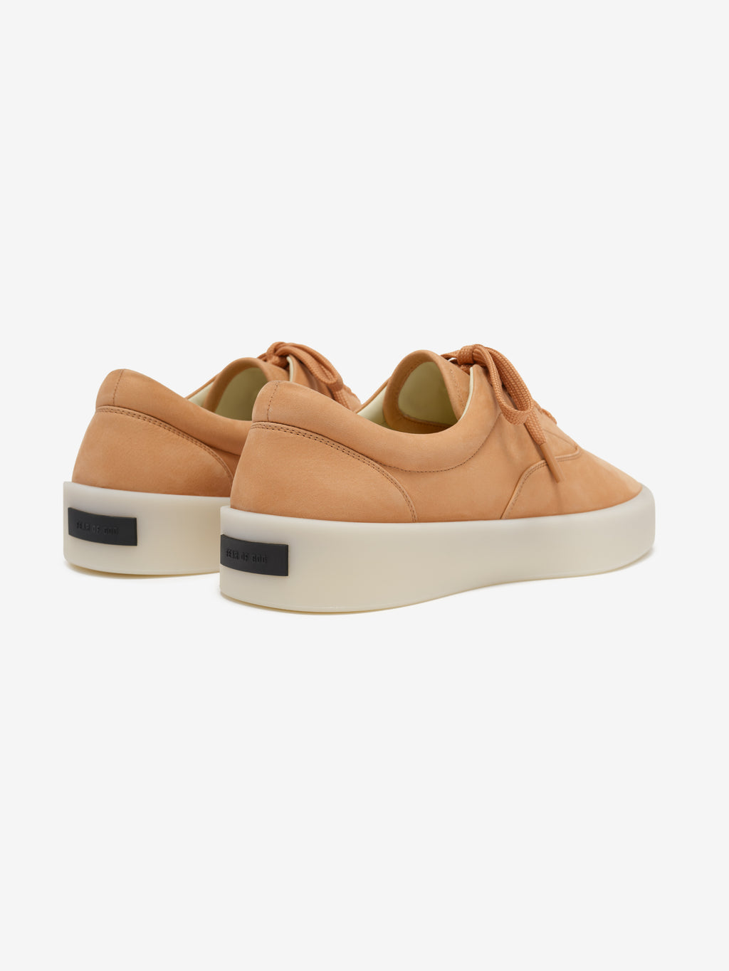 pair of tan nubuck low-top sneakers with thick white sculpted rubber soles and tonal laces viewed from rear side angle