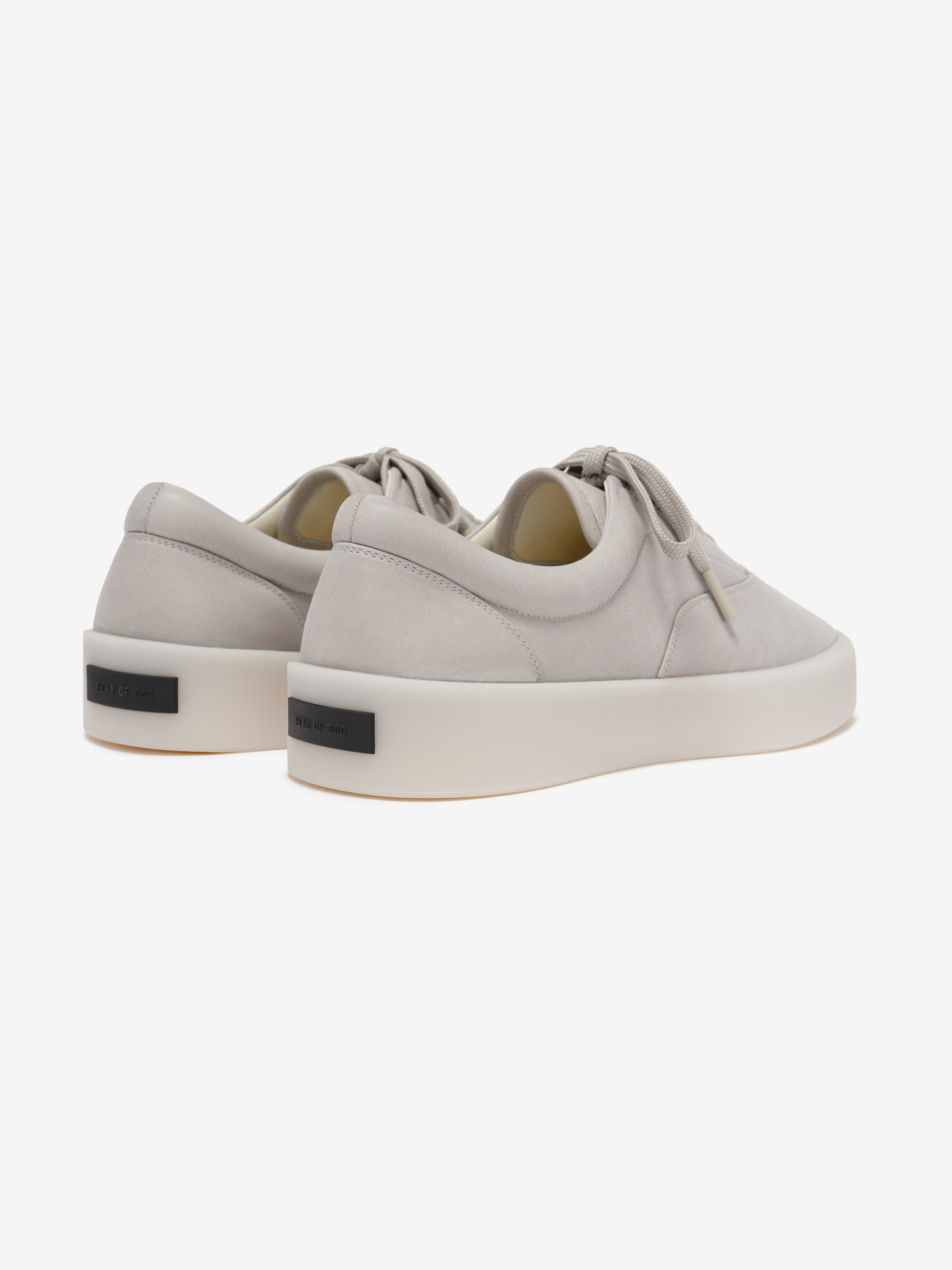 pair of light beige Italian suede low-top sneakers with thick off-white sculpted rubber soles viewed from rear angle