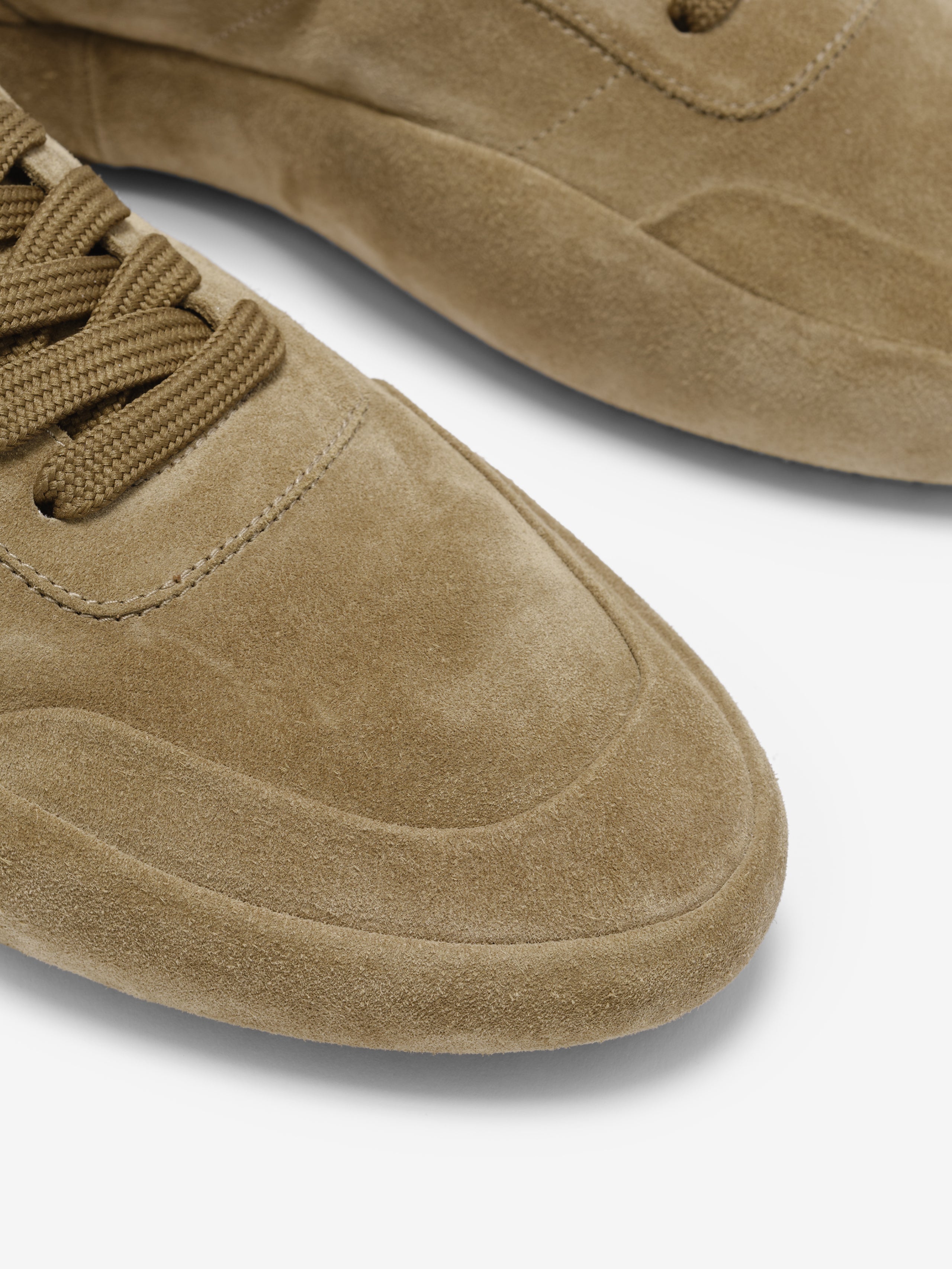 close-up of taupe suede Lace Up Runner sneaker toe area with tonal laces and stitched detailing on white background