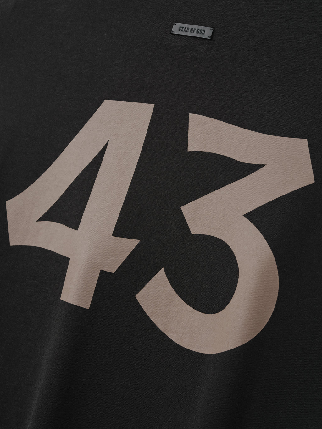 close-up of black cotton-rayon tee with large taupe hand-printed "43" graphic and Fear of God label near neckline
