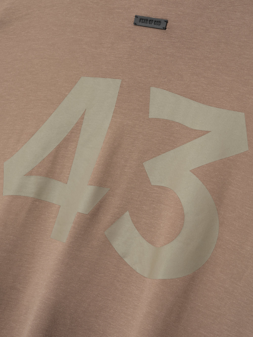 close-up of taupe cotton-rayon fabric with large off-white "43" printed and small Fear of God label near neckline