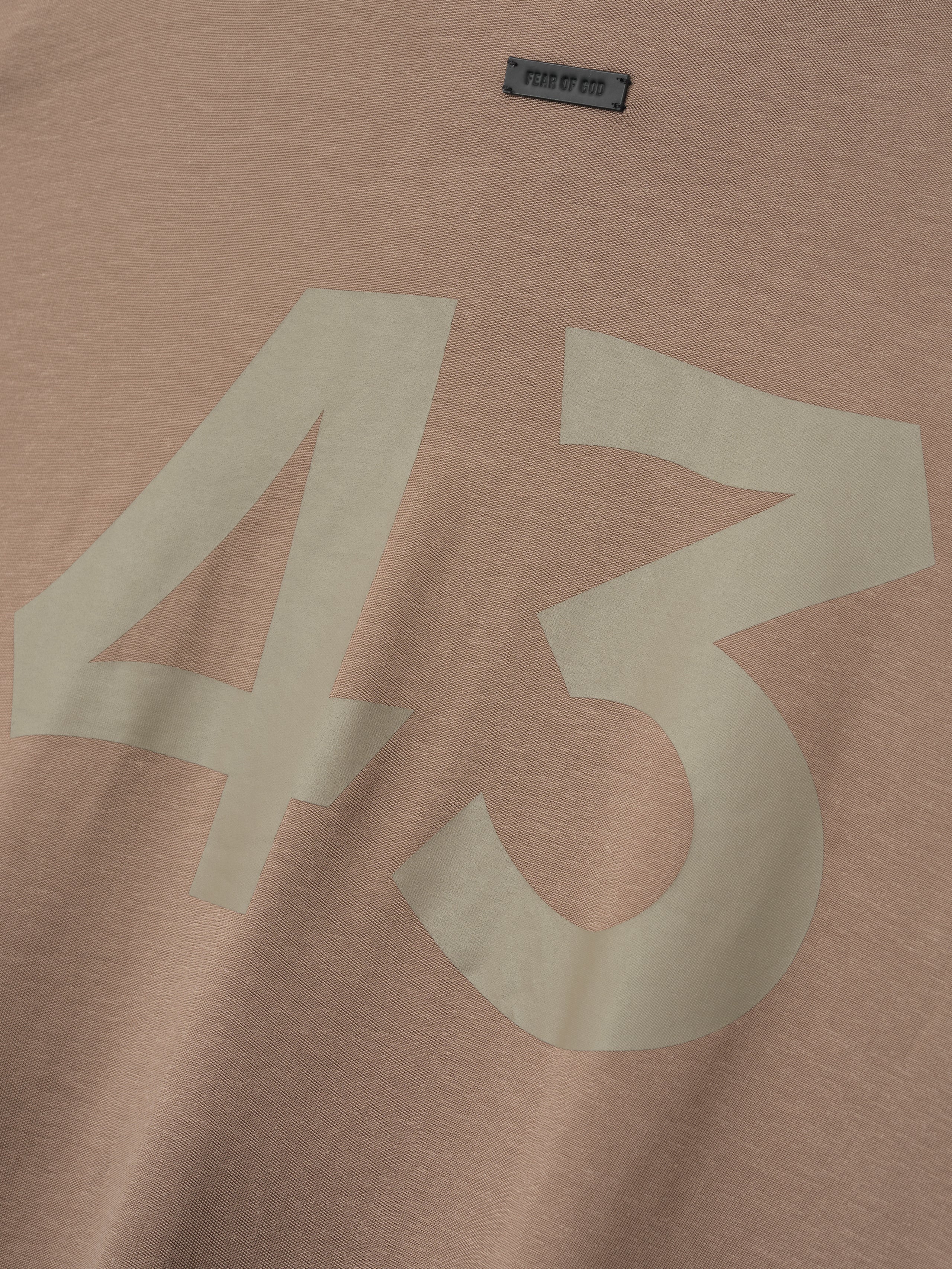 close-up of taupe cotton-rayon fabric with large off-white "43" printed and small Fear of God label near neckline