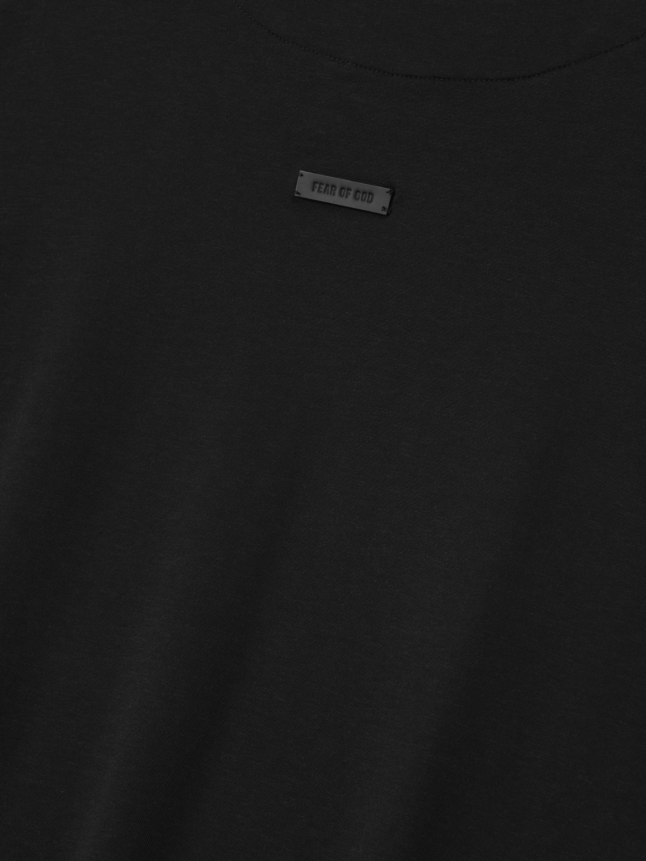 close-up of black cotton-rayon tee with minimal Fear of God label centered below the crew neck