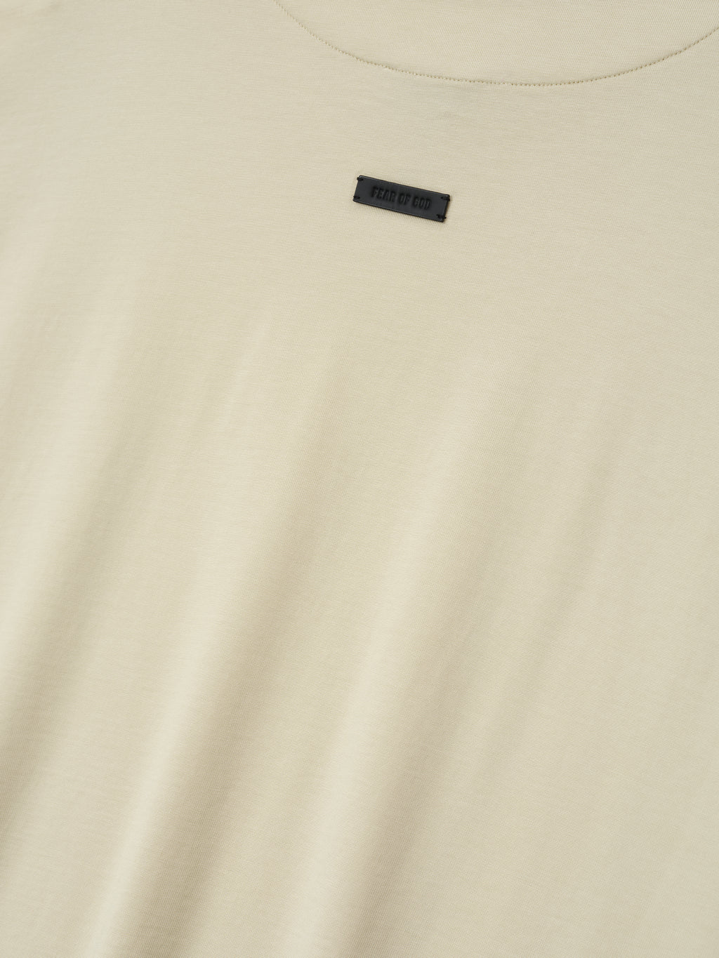 off-white cotton-rayon crew neck tee with soft stone wash and small black Fear of God label centered near neckline
