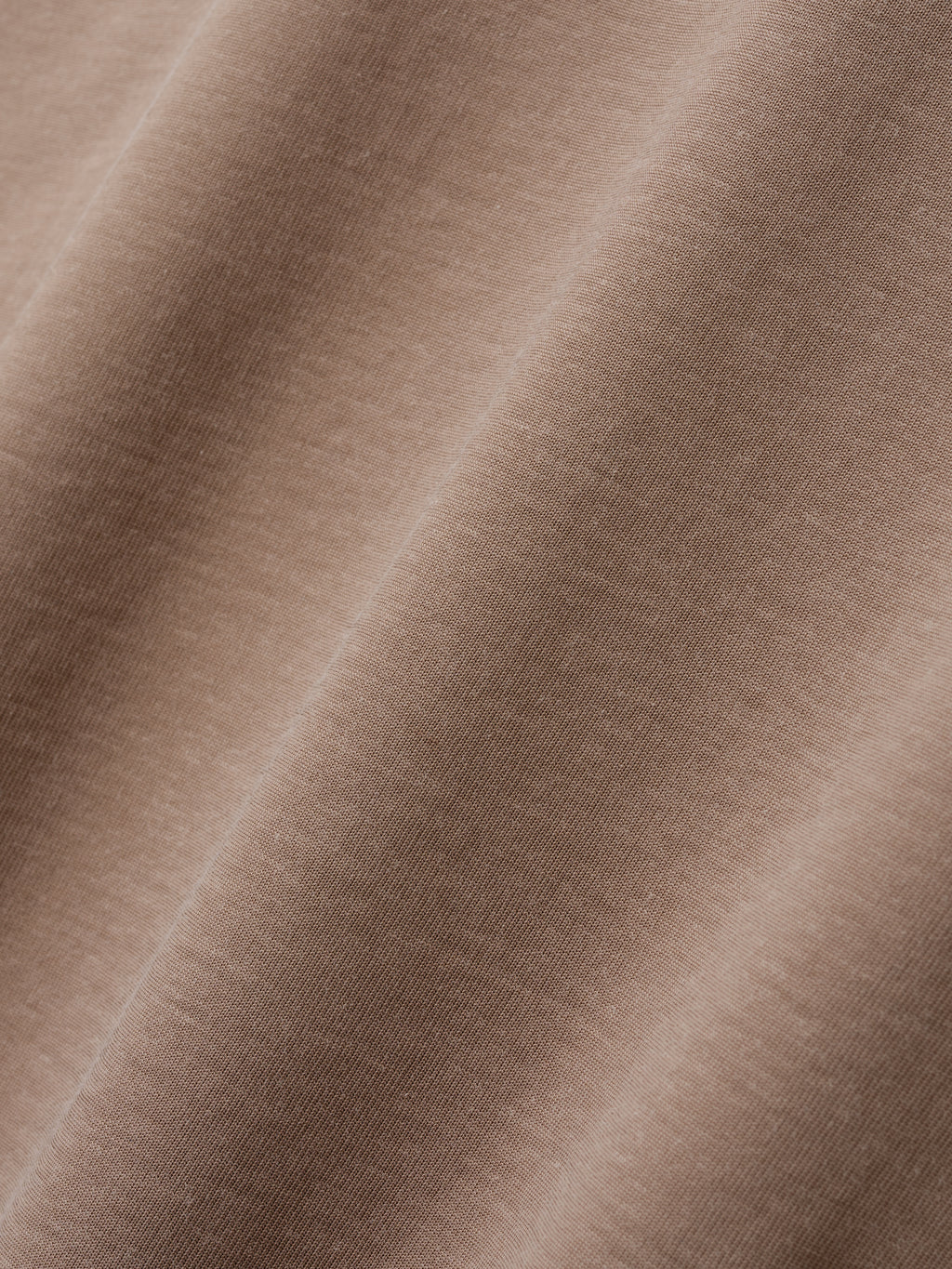 Close-up of soft, smooth fabric in a muted warm beige tone with subtle texture details visible