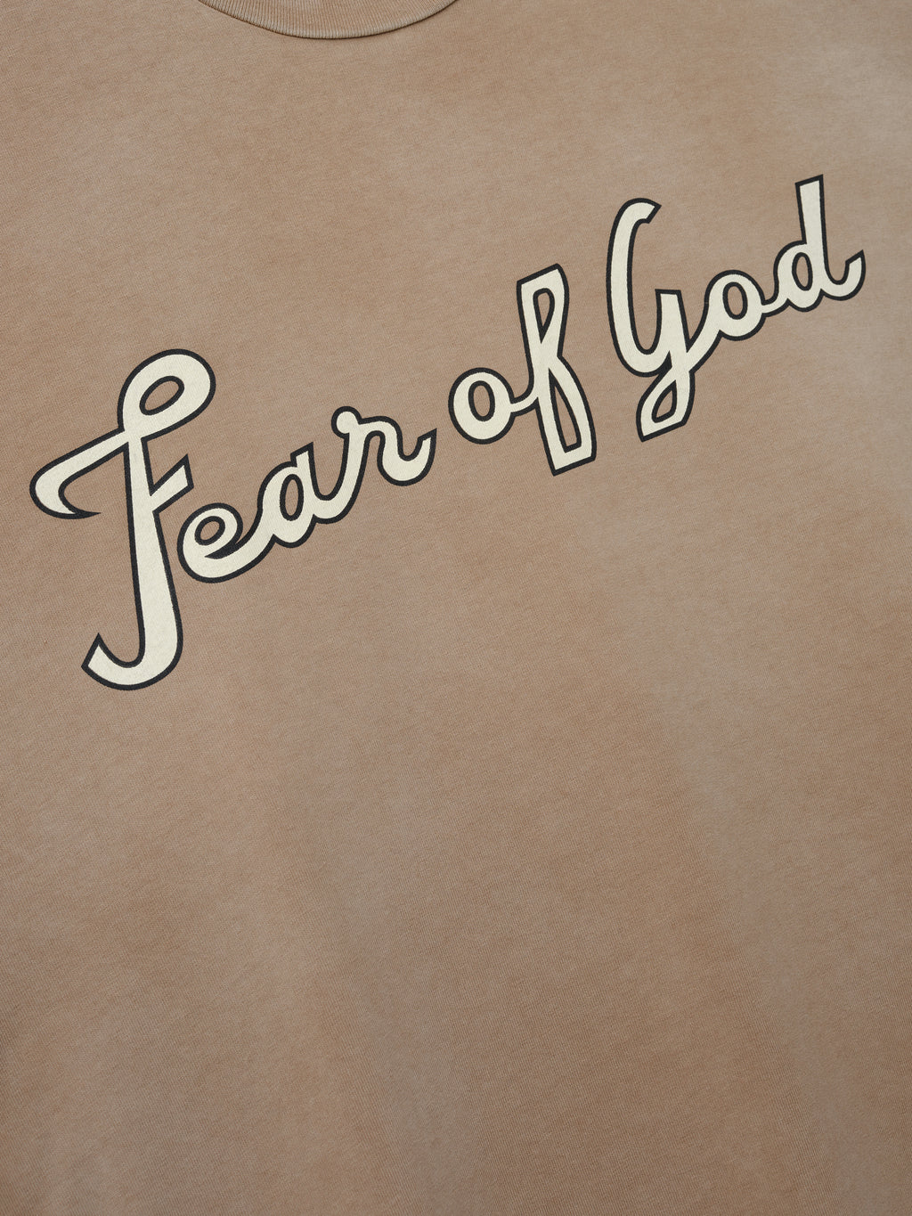 close-up of faded beige heavyweight cotton jersey tee with diagonal cursive "Fear of God" graphic on chest
