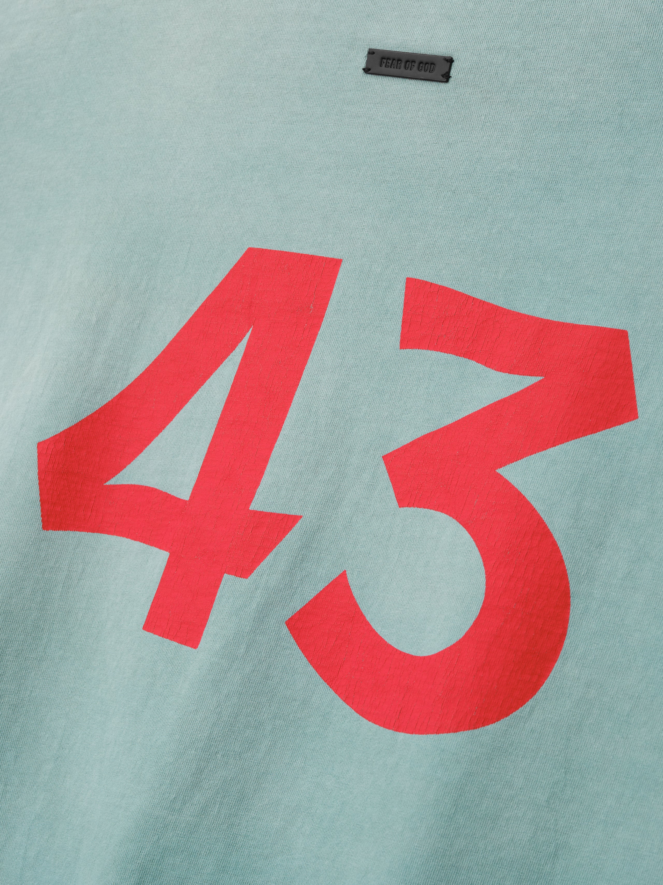 Close-up of sky blue fabric with large bold red number 43 printed on the front and small black label above