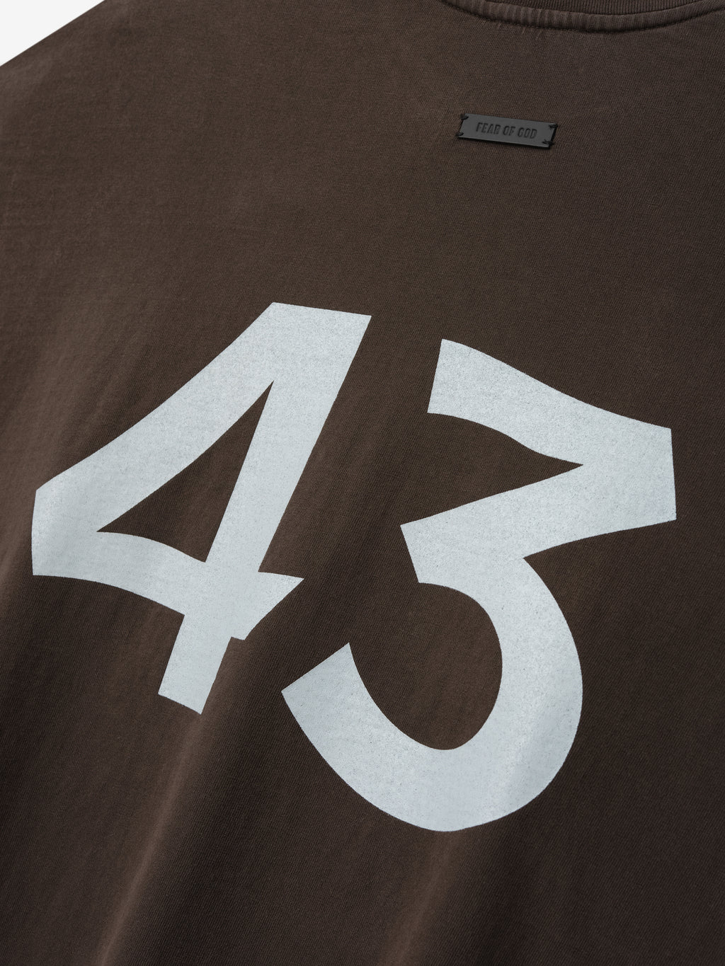 Close-up of dark brown shirt with large bold white number 43 printed on the front and small label above neckline