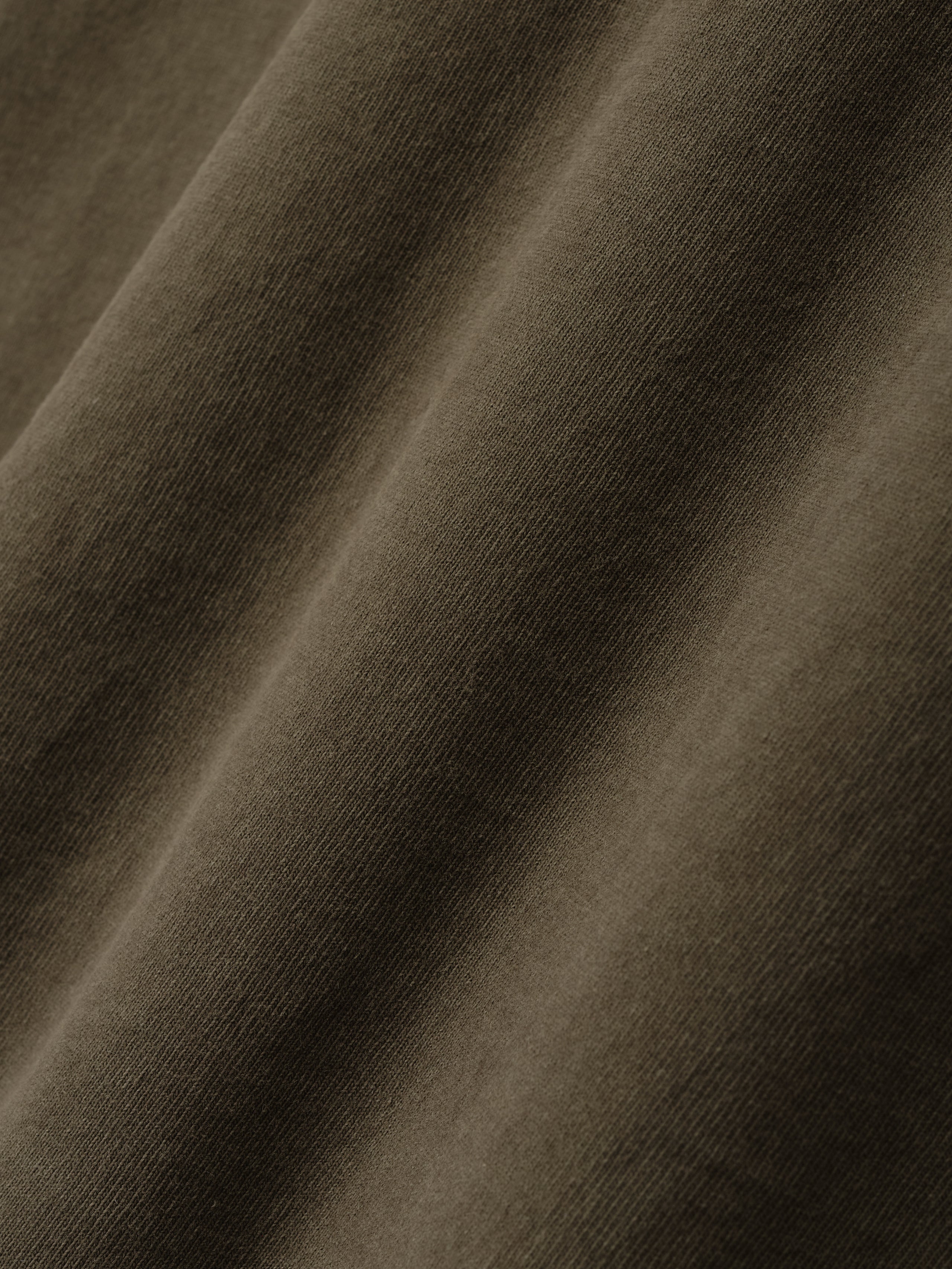 Detailed close-up of smooth, faded brown cotton fabric showing fine knit texture and soft folds