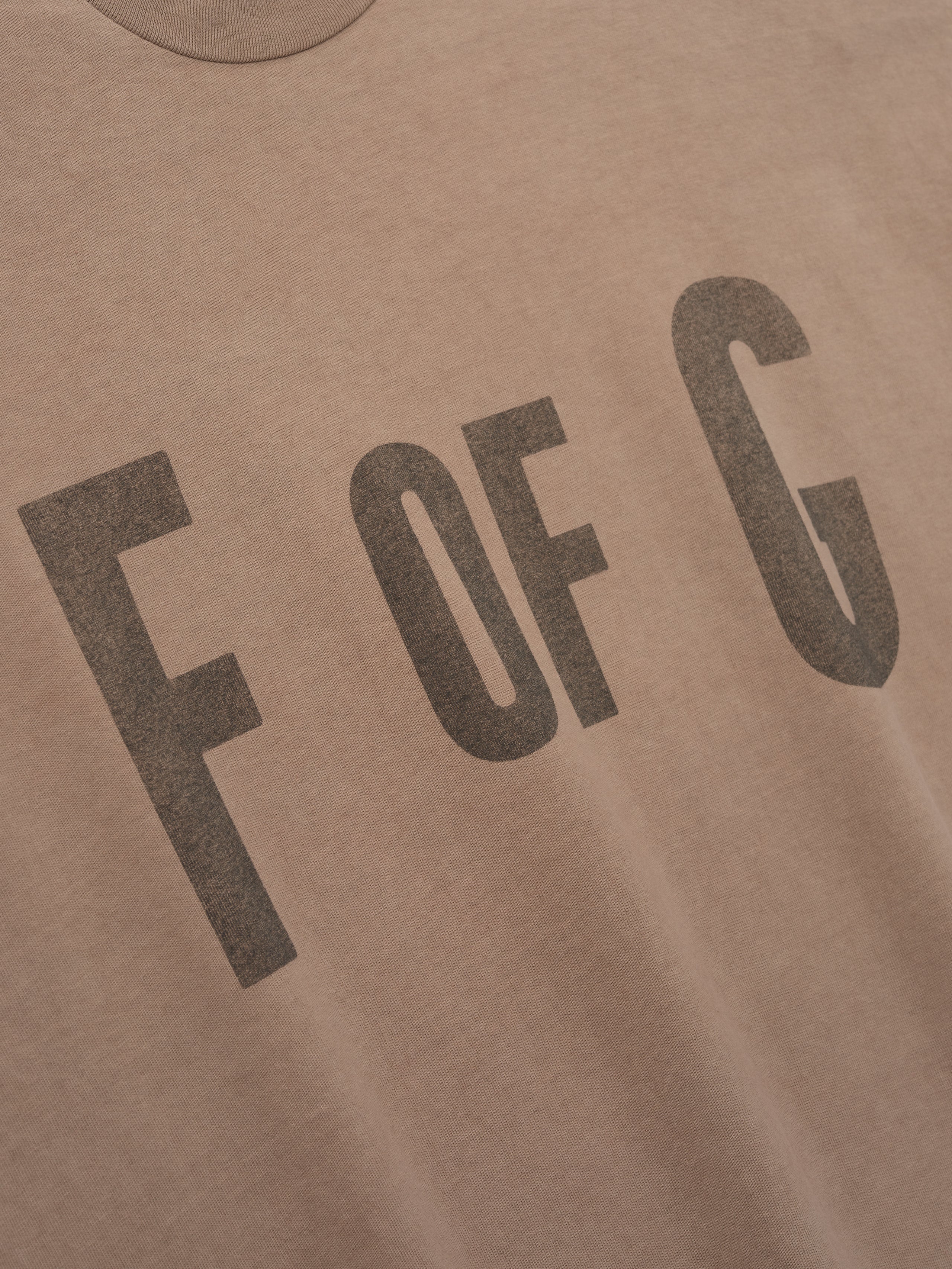 close-up of garment-washed heavyweight cotton tee with faded vintage-style "F OF G" print on front chest