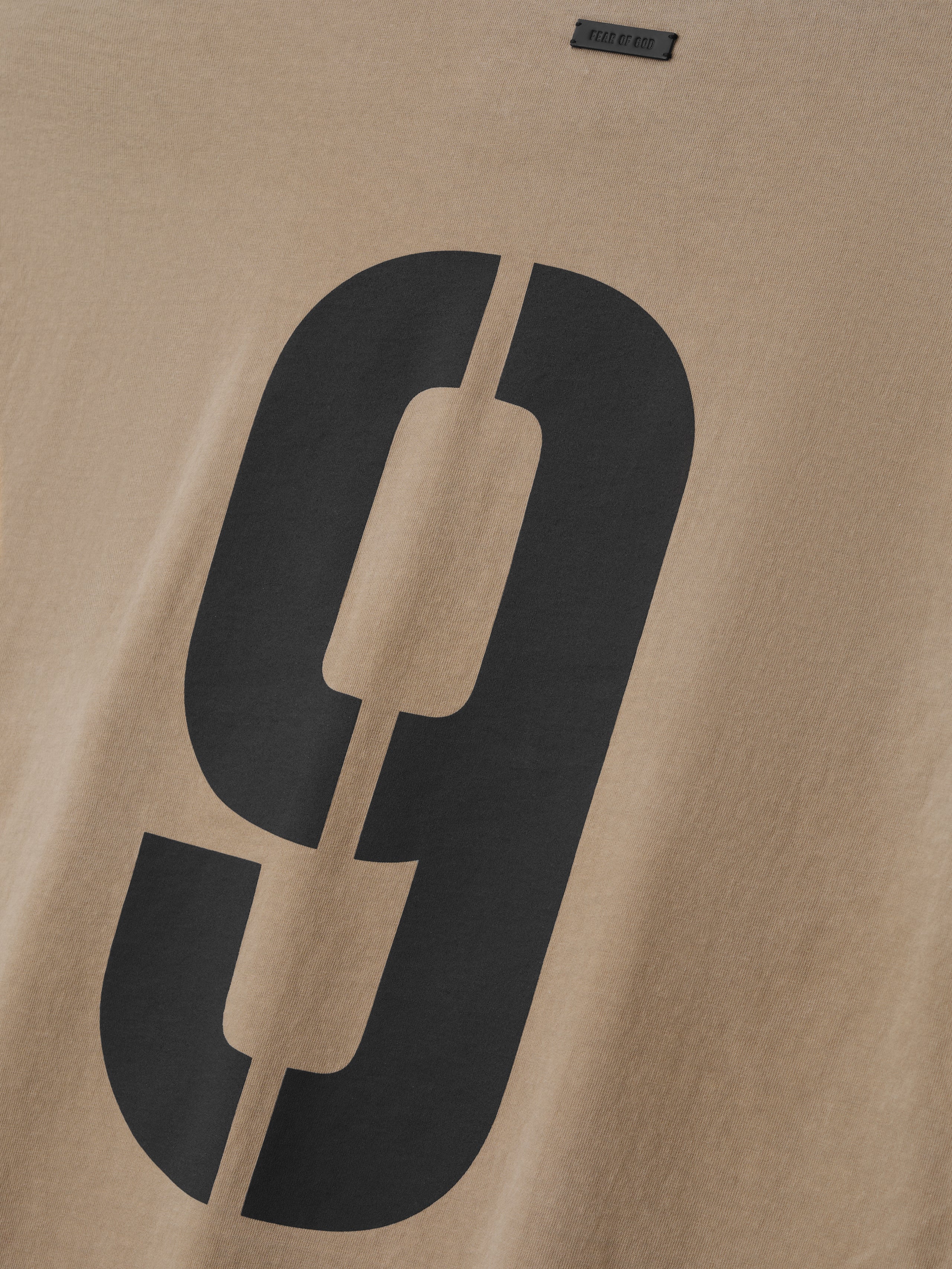 Close-up of beige fabric with large black number 9 split vertically and a small rectangular label above it