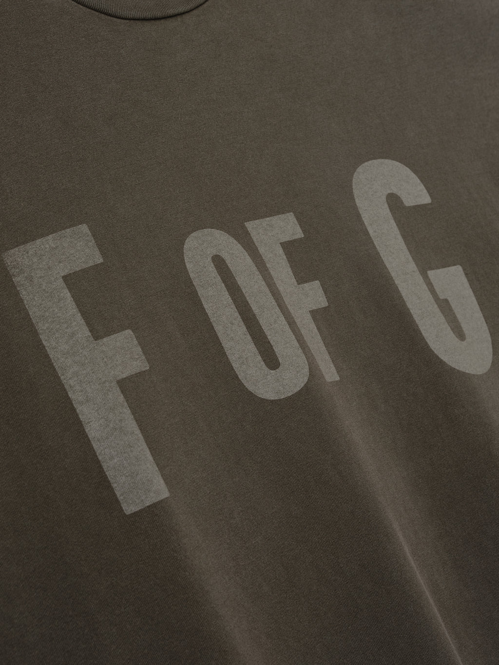 Close-up of a faded brown crewneck shirt with large "F OF G" text printed across the chest panel