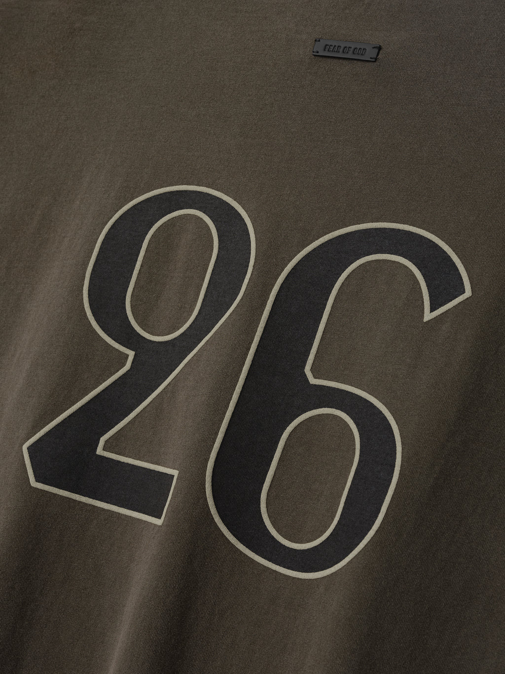 Close-up of faded brown fabric with large black and beige outlined number "26" printed on the surface