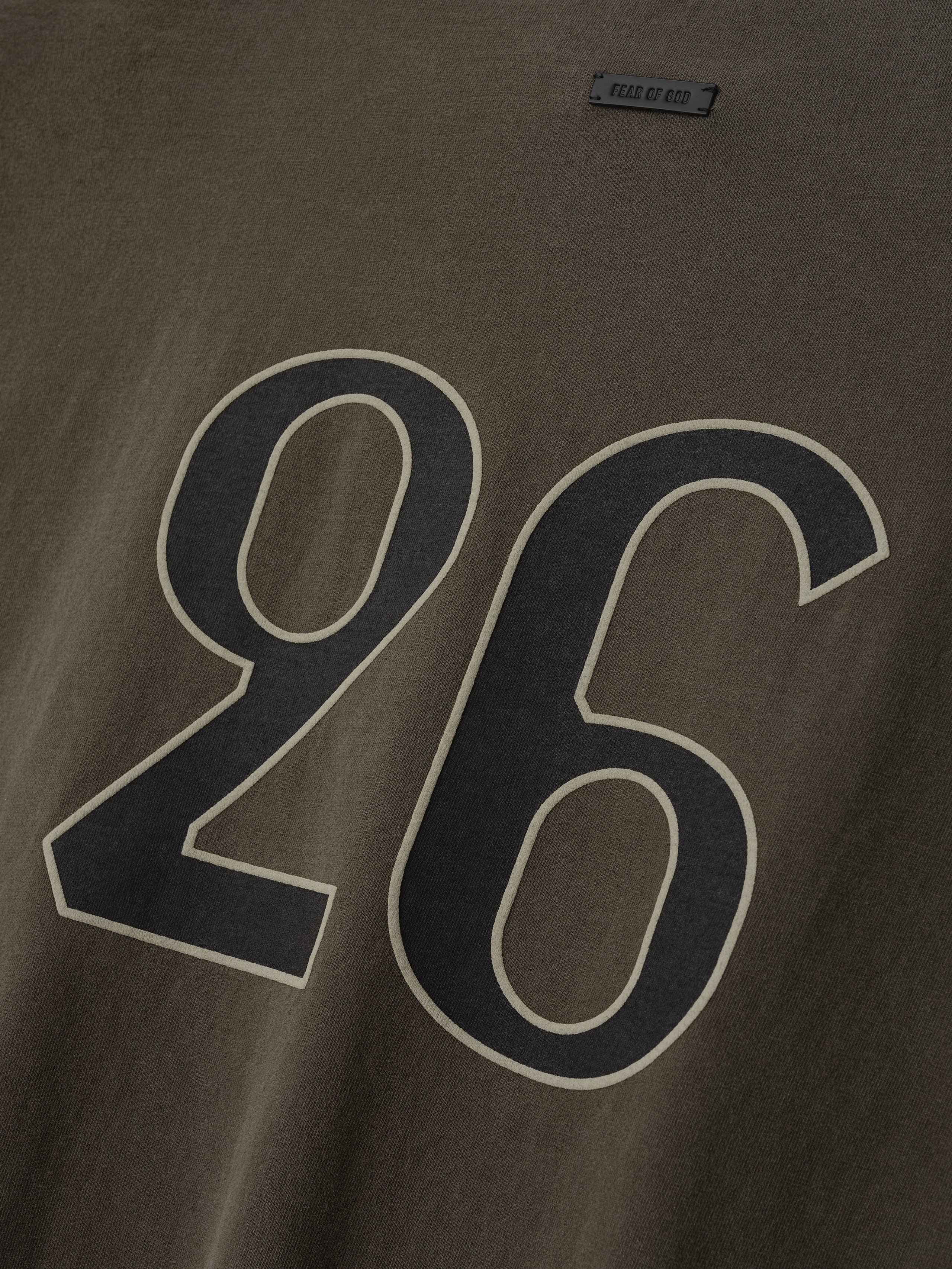 Close-up of faded brown fabric with large black and beige outlined number "26" printed on the surface