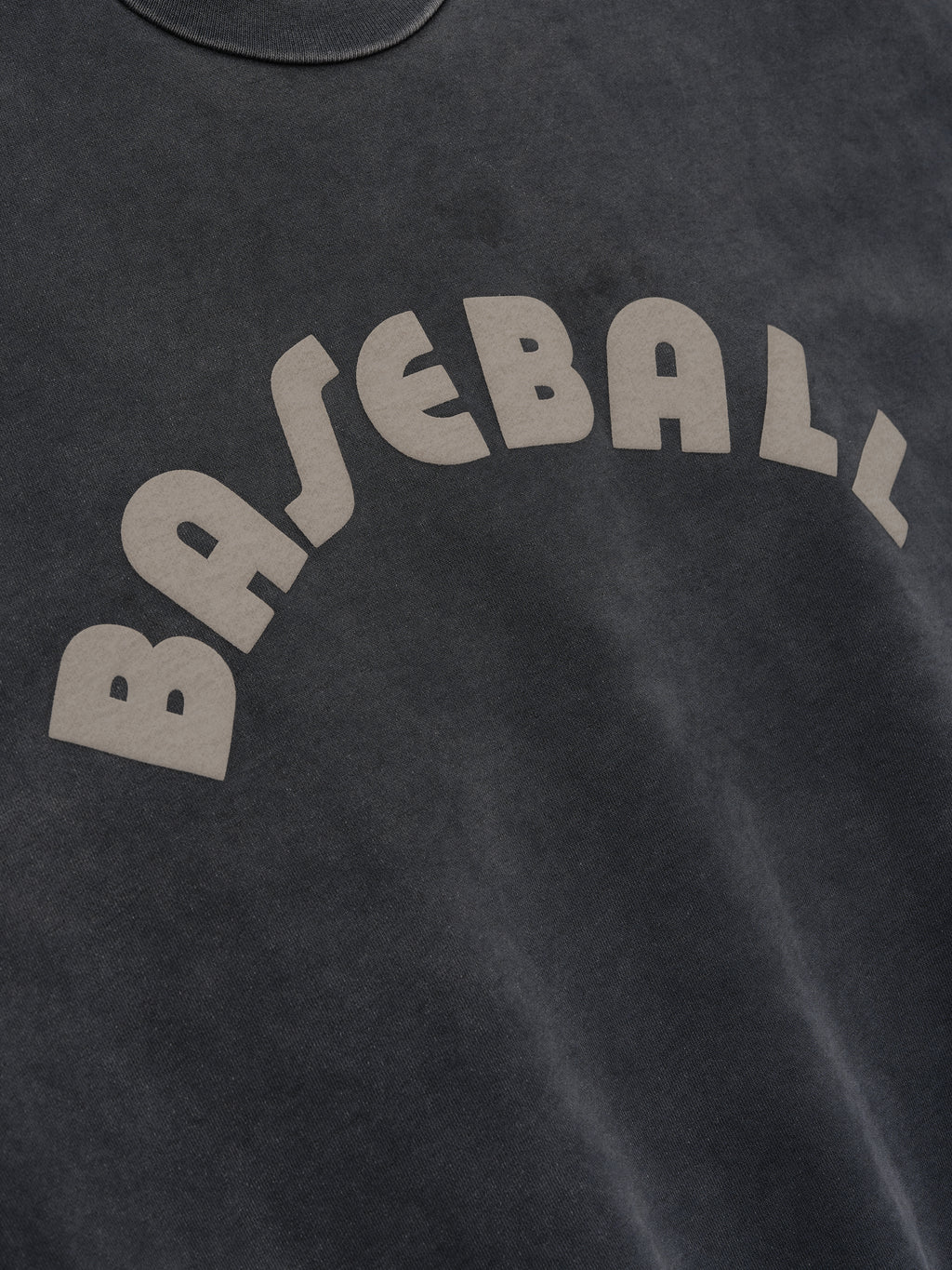 Close-up of off-black cotton fabric with beige "BASEBALL" text printed in an arched design on soft material