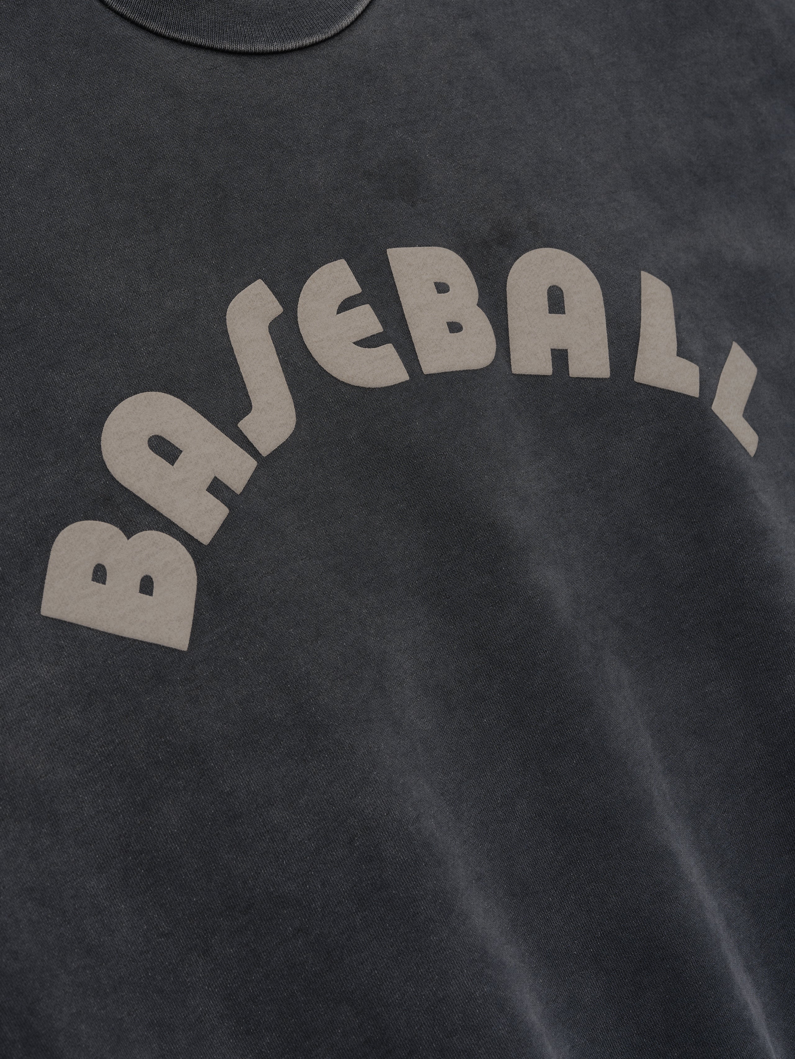 Close-up of off-black cotton fabric with beige "BASEBALL" text printed in an arched design on soft material