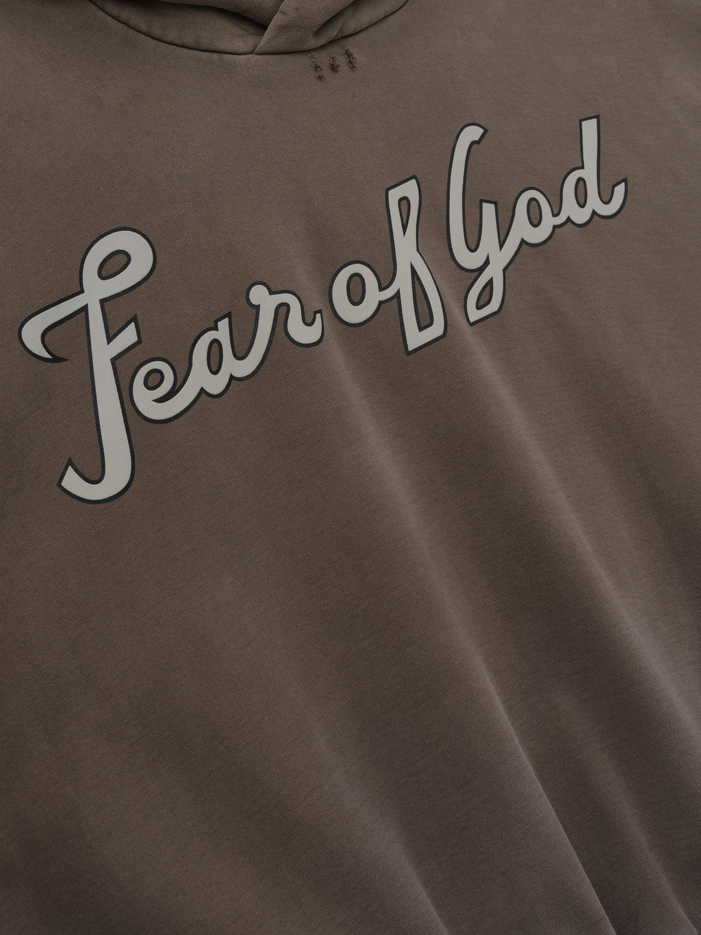 close-up of garment-washed heavyweight cotton fleece hoodie with hand-painted "Fear of God" script on chest