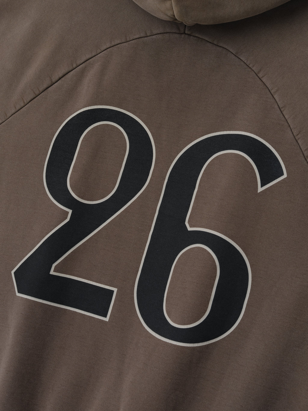 close-up of garment-washed brown heavyweight cotton fleece hoodie with large black outlined "26" graphic on back