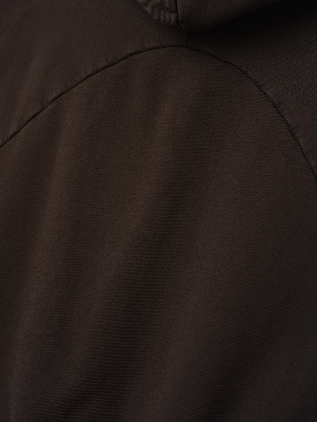 close-up detail of dark brown heavyweight cotton fleece fabric with curved seam of half raglan sleeve hoodie