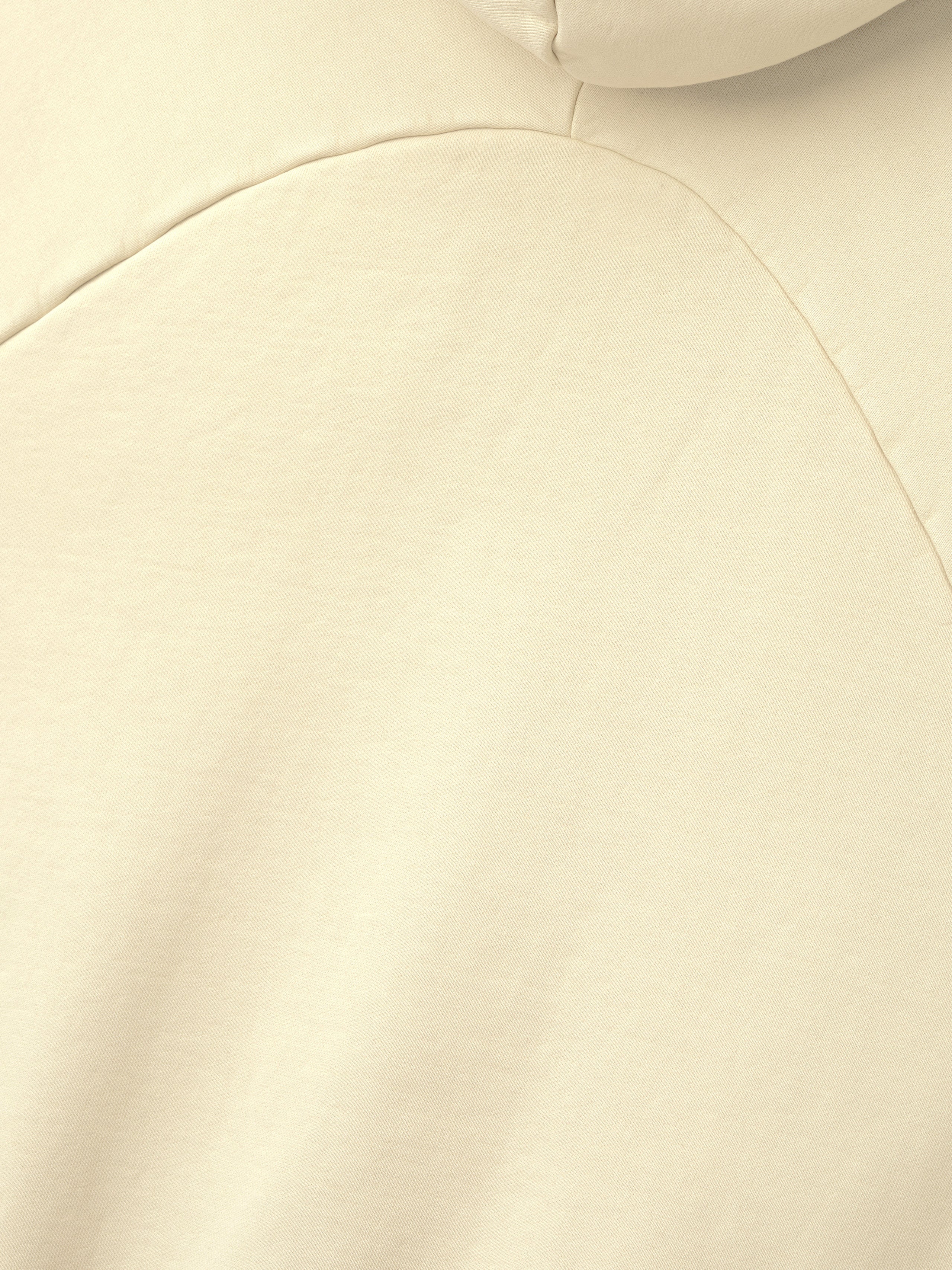 close-up of off-white heavyweight cotton fleece fabric with half raglan seam and smooth vintage wash finish