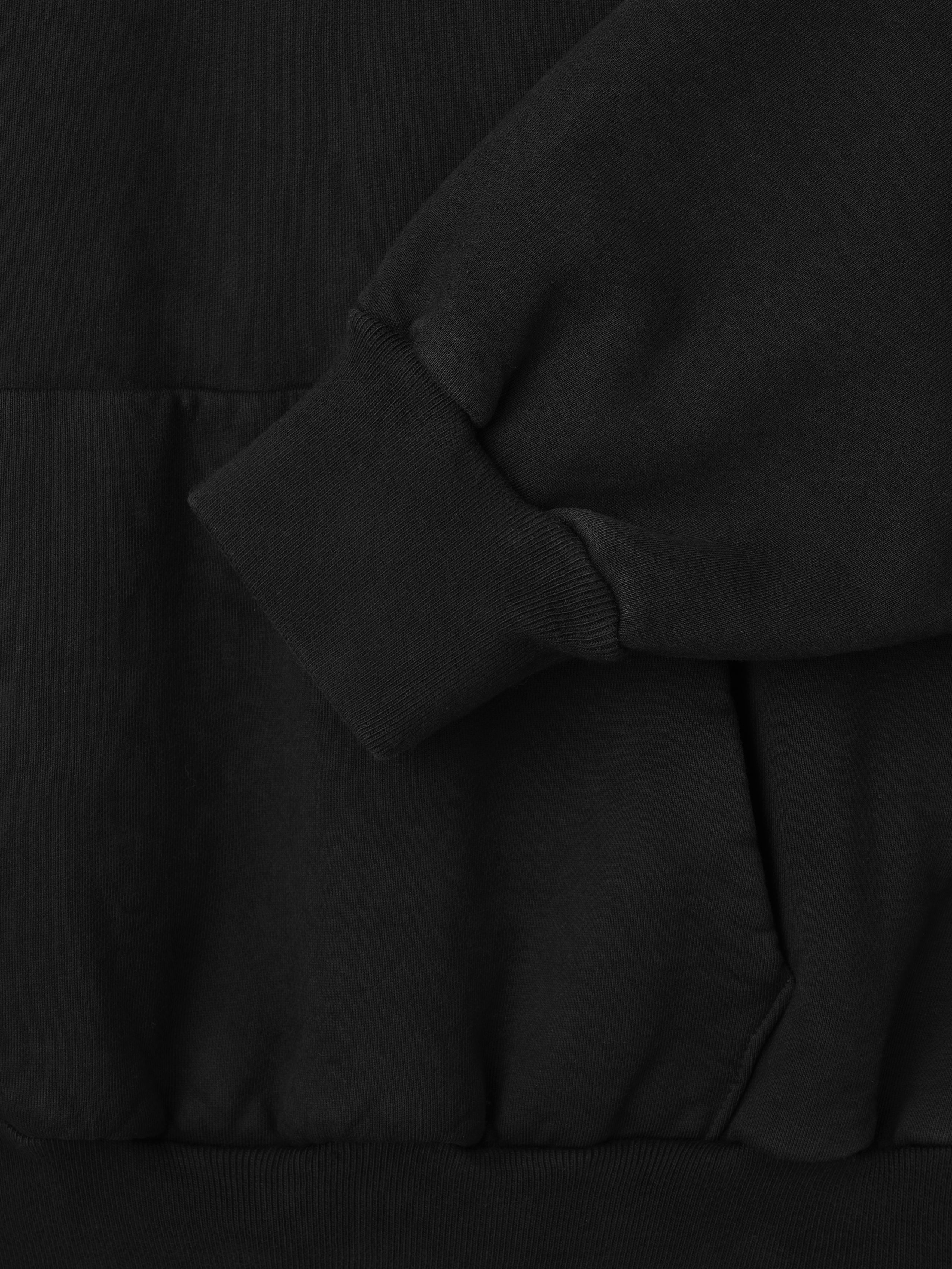 close-up of black heavyweight cotton fleece hoodie cuff and front pocket with ribbed hem detailing