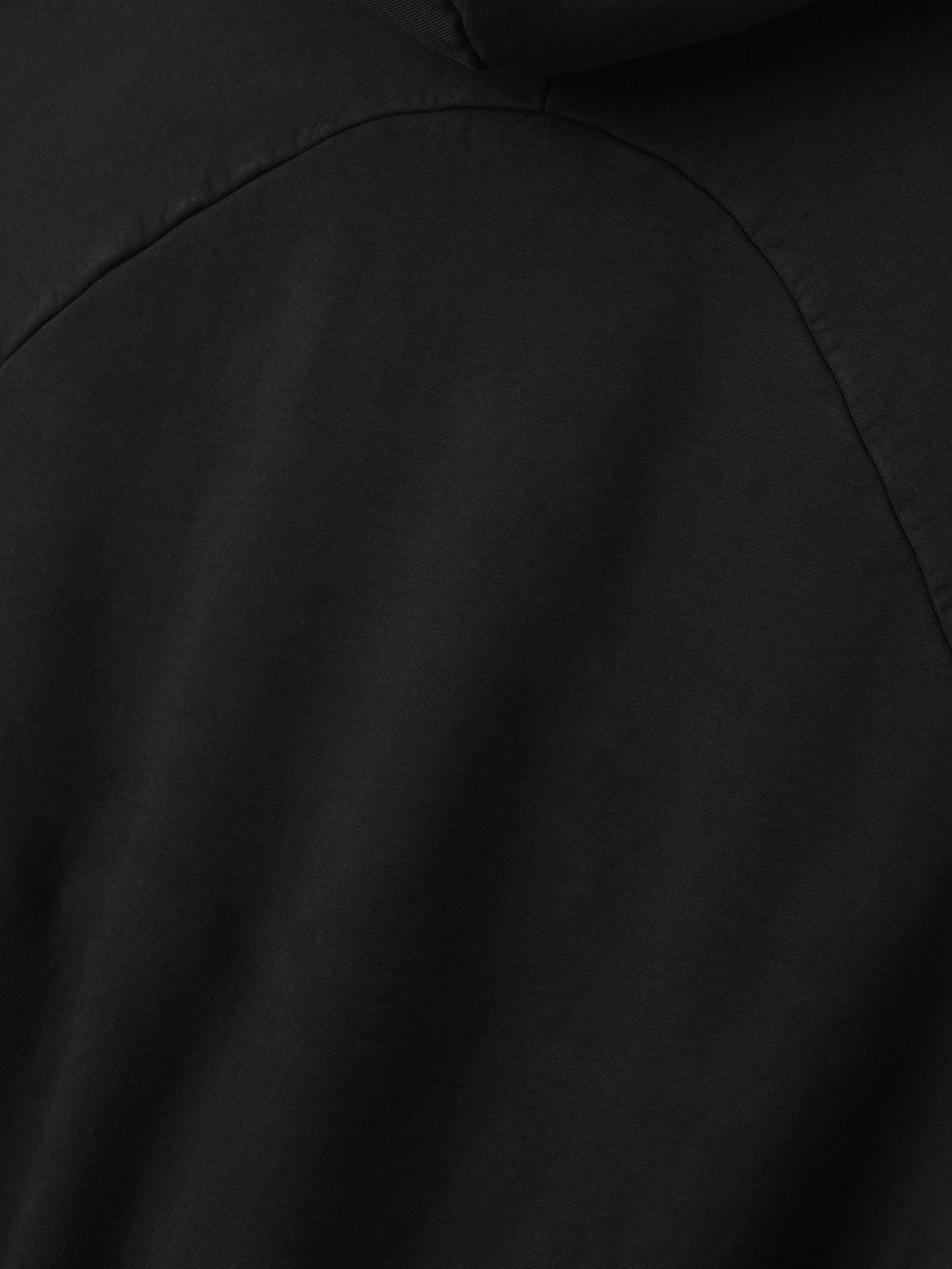 close-up of black heavyweight cotton fleece fabric and curved seam detail of half raglan sleeve hoodie back