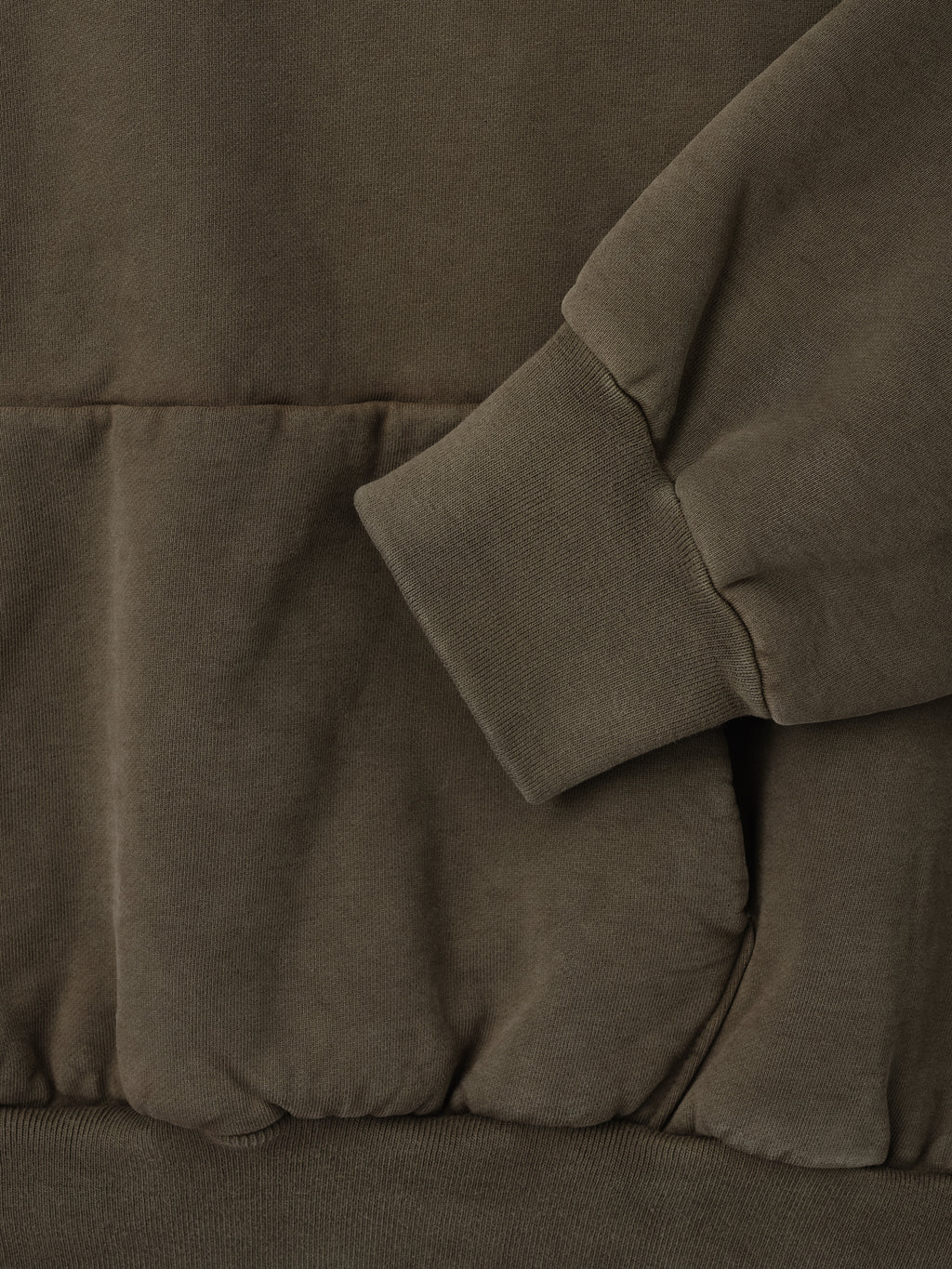 Close-up of faded brown sweatshirt showing ribbed cuff, kangaroo pocket, and soft textured fabric detail