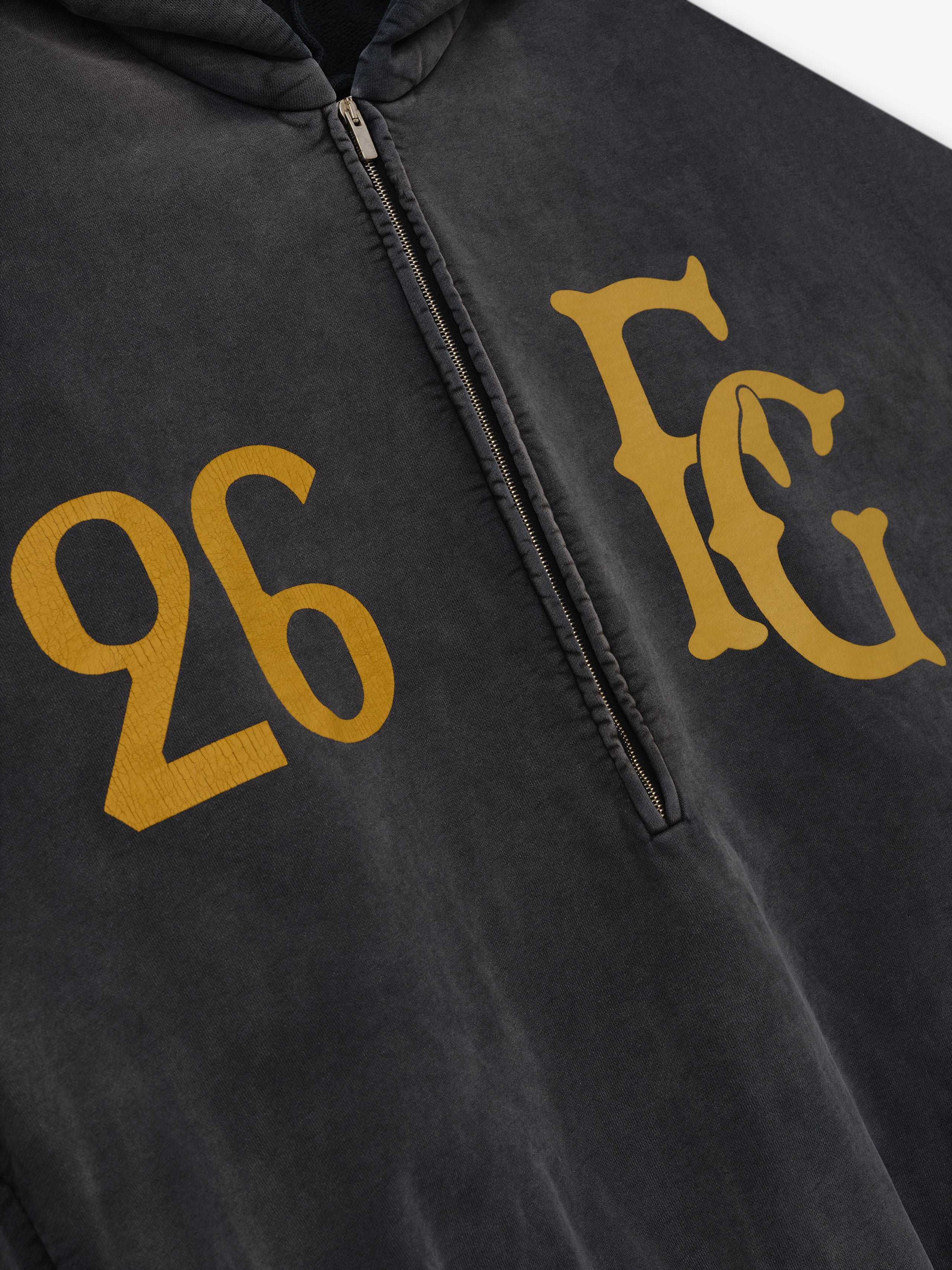 Off-black washed cotton half-zip hoodie with large gold "26" and stylized "FG" letters on chest
