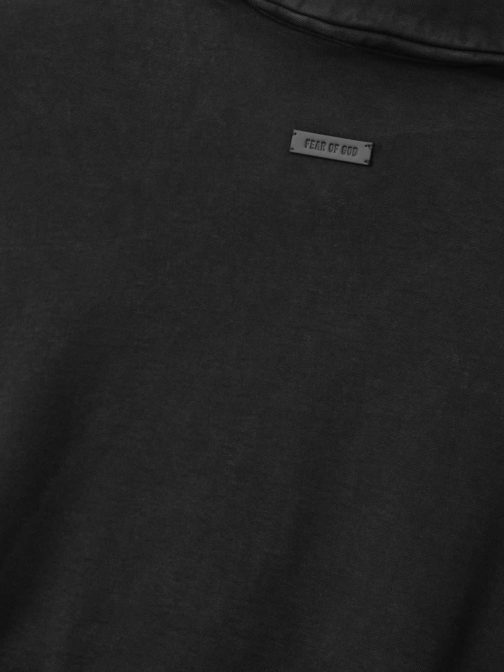 close-up of dark sunfaded cotton fleece fabric with small rectangular Fear of God logo patch on sweatshirt back